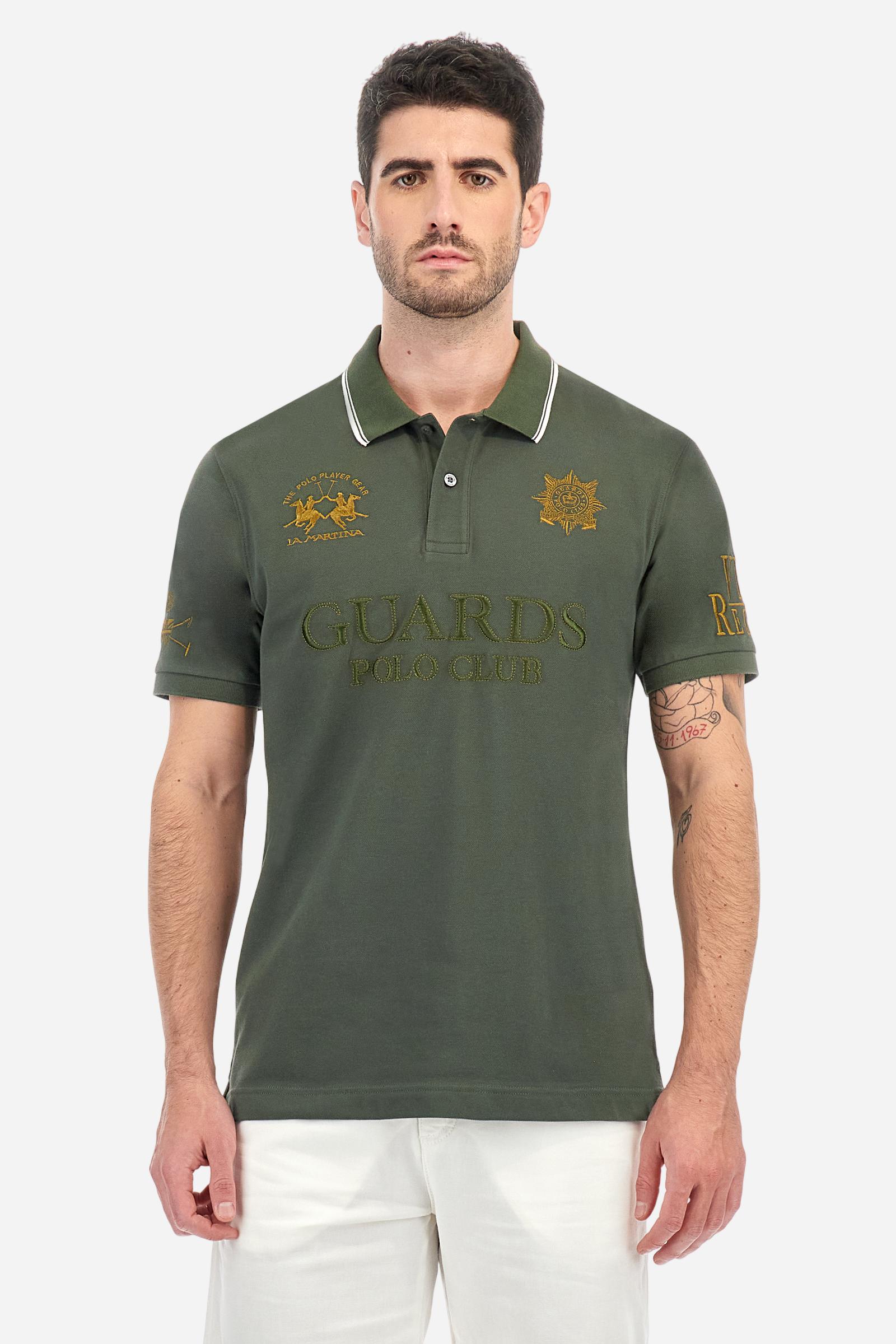 Men's short-sleeved Guards polo shirt in a single colour, made of cotton piqué. Fastens with two buttons. The collar is ribbed with striped trim in a contrasting colour. The graphics on the chest and sleeves are all made using the embroidery technique. The central lettering on the chest is a 3D embroidery in the same colour as the base fabric. The large colour-contrasting logo is embroidered on the chest. The fit is regular. The model is wearing a size L. - Thyme