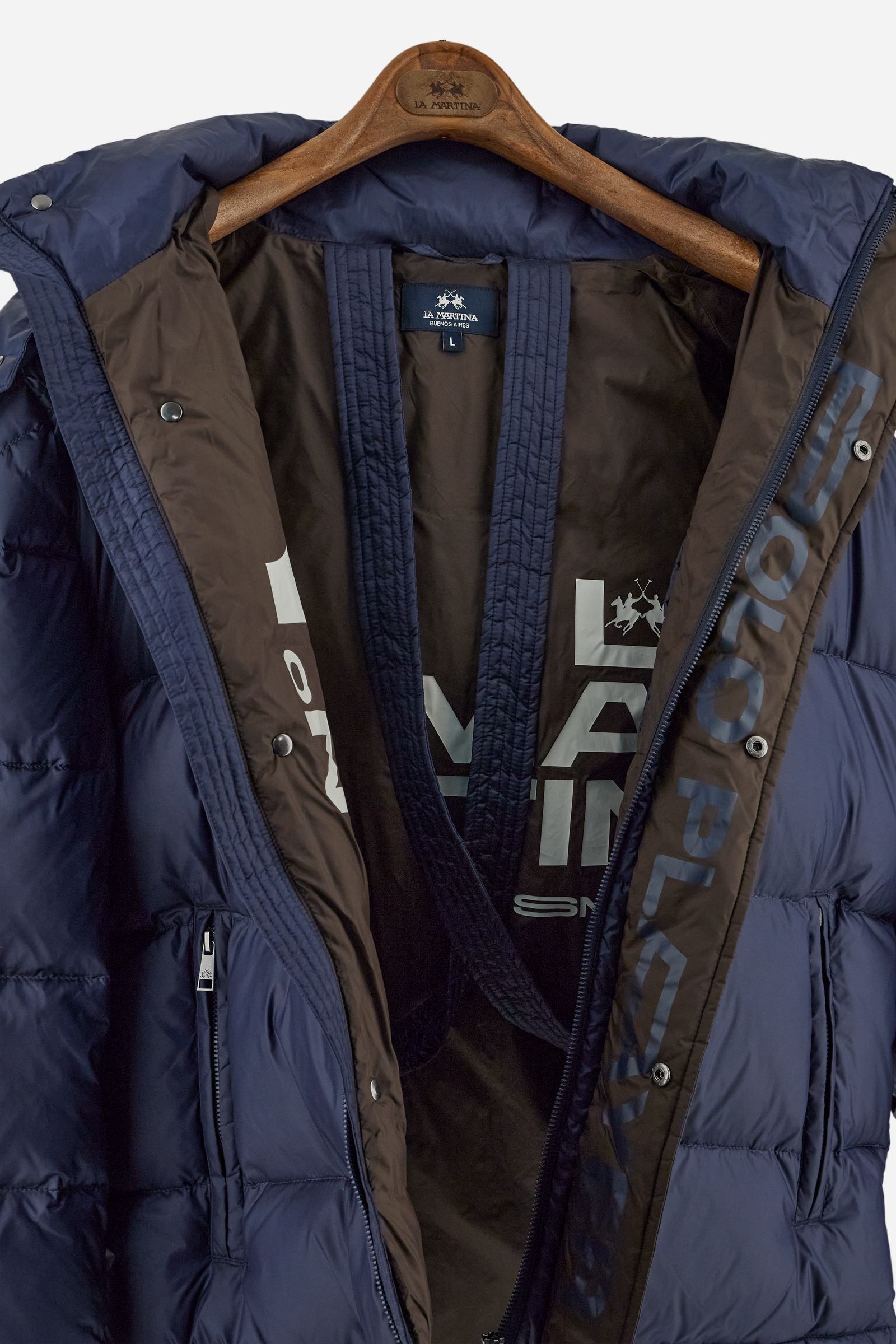 Men’s padded bomber jacket with detachable hood. Made of solid iridescent nylon with contrast lining. Equipped with two practical inner braces for extra comfort. Double customized zip front closure with inner placket featuring contrast Polo Player print, closed with metal snap buttons. Two vertical zipped pockets on the front. Hood with contrast lining and adjustable elastic drawstring. Bold Polo Player graphics printed inside. Regular fit for comfortable movement without bulk. Model wears size L. - Navy