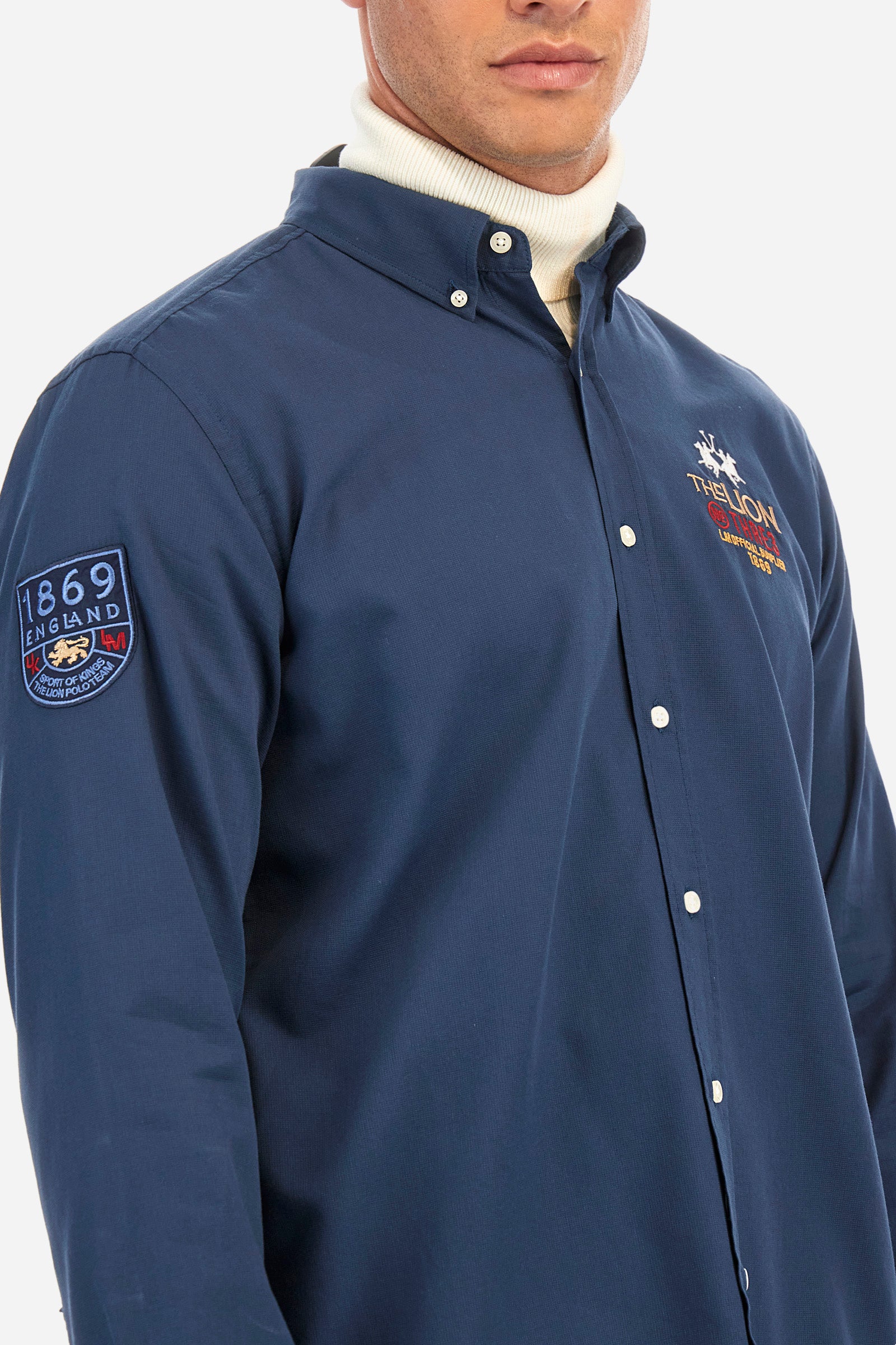 Men's plain long-sleeved shirt, made from 100% cotton. Button-down collar. The brand logo and name are embroidered on the front, alongside another iconic symbol. Regular fit. The model is wearing a size L. - Navy