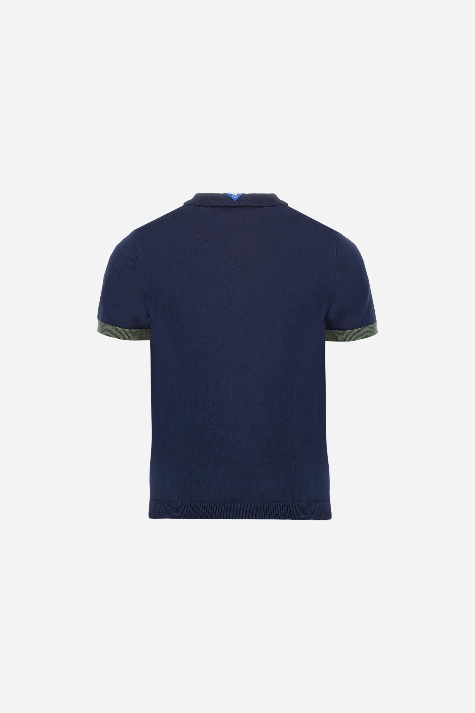 Men's two-tone short-sleeved knitted polo shirt made of 100% cotton. The cuffs are contrasting, while the waistband is in the same tone, but both are ribbed. The applied bands on the sleeve and shoulders are knitted in a contrasting colour. Contrasting details are present on the neck opening and inside the collar as a decorative motif. Small embroidered lettering on the front. The logo is embroidered in a contrasting colour on the chest, left side. The fit is regular. The model is wearing a size L. - Navy