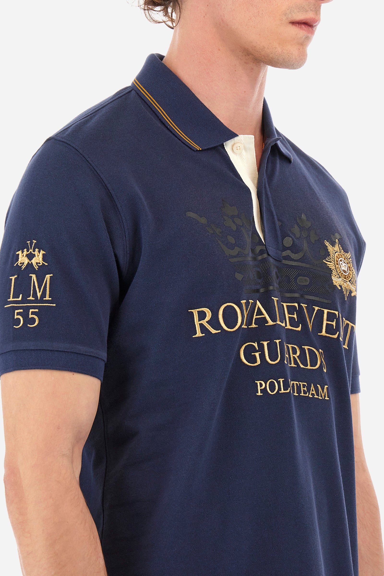 Men's single-colour short-sleeved polo shirt in 100% cotton. Two-button fastening. Collar with two contrasting stripes and ribbed armholes. On the front we find lettering and the symbol representing the Guards line. The brand's initials, the number 55 and the logo are embroidered on one of the sleeves. The fit is regular. The model wears a size L. - Navy