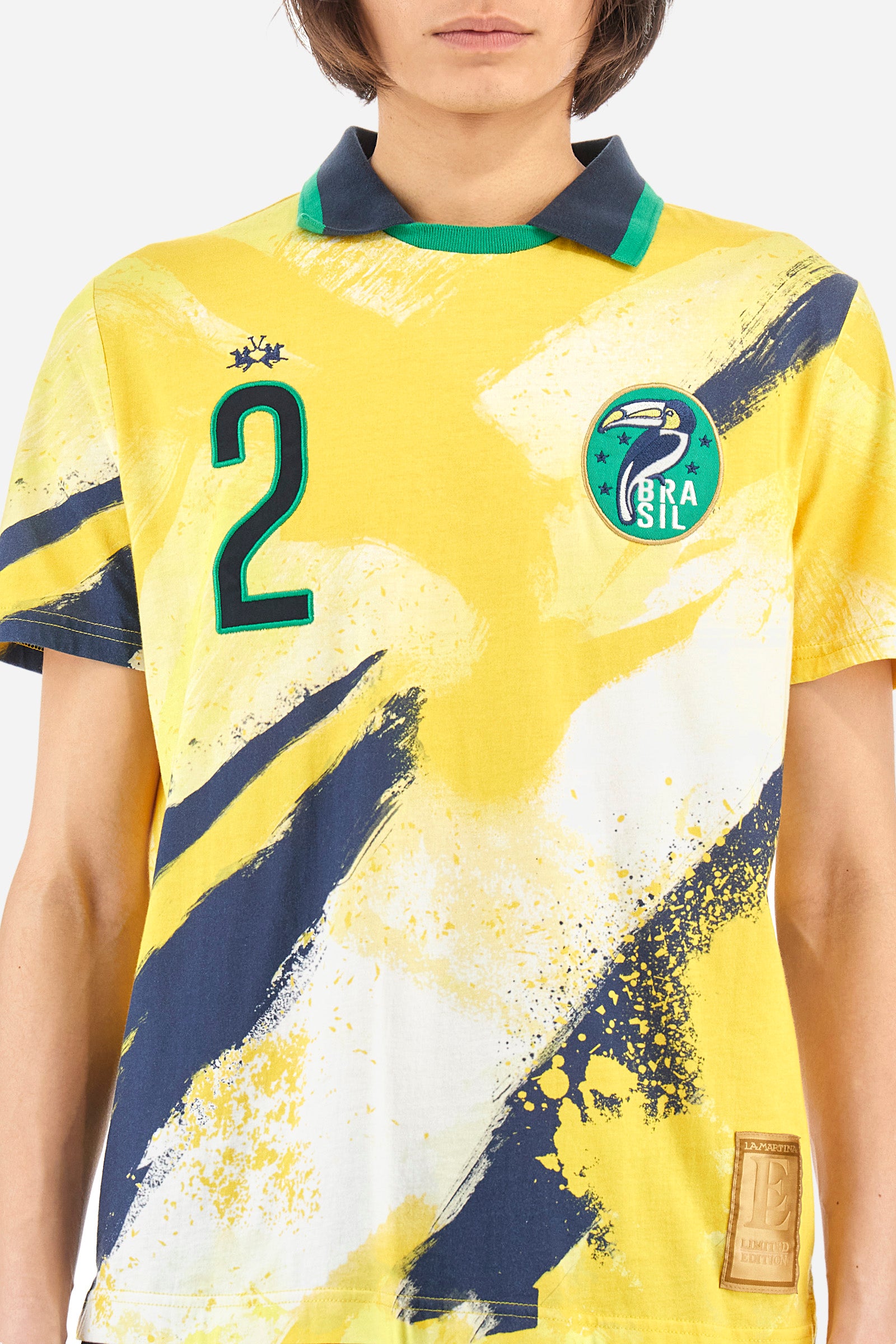 Men's multi-coloured short-sleeved polo shirt in 100% cotton. Crew-neck polo shirt with pointed collar featuring the representative colours of Brazil. On the chest there is a patch with the number 2 and a patch with a characteristic symbol of the nation. On the back we find the word "Brazil", the number two and other symbols. The logo is embroidered on both the front and back. The fit is regular. The model wears a size L. - SulphurSpring/OptWhi