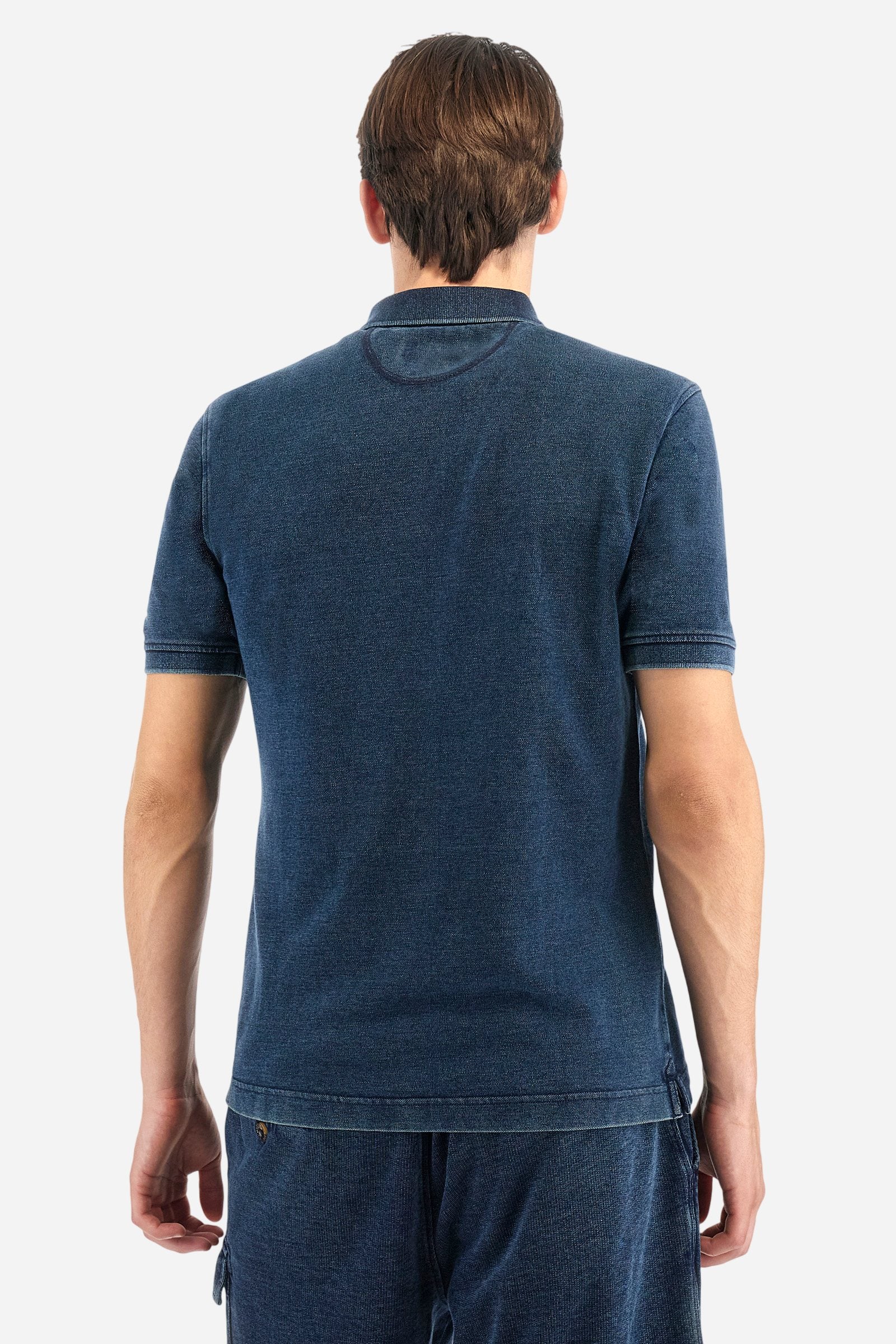 Men's short-sleeved polo shirt made of 100% cotton indigo pique. Fastens with two buttons. The collar and cuffs are folded and are made of ribbed fabric. Garment treated with enzyme washing, which gives the faded and lived-in look typical of denim. The contrasting embroidered logo is present on the left side of the chest. Regular fit. The model is wearing a size L. - Dark Indigo Denim