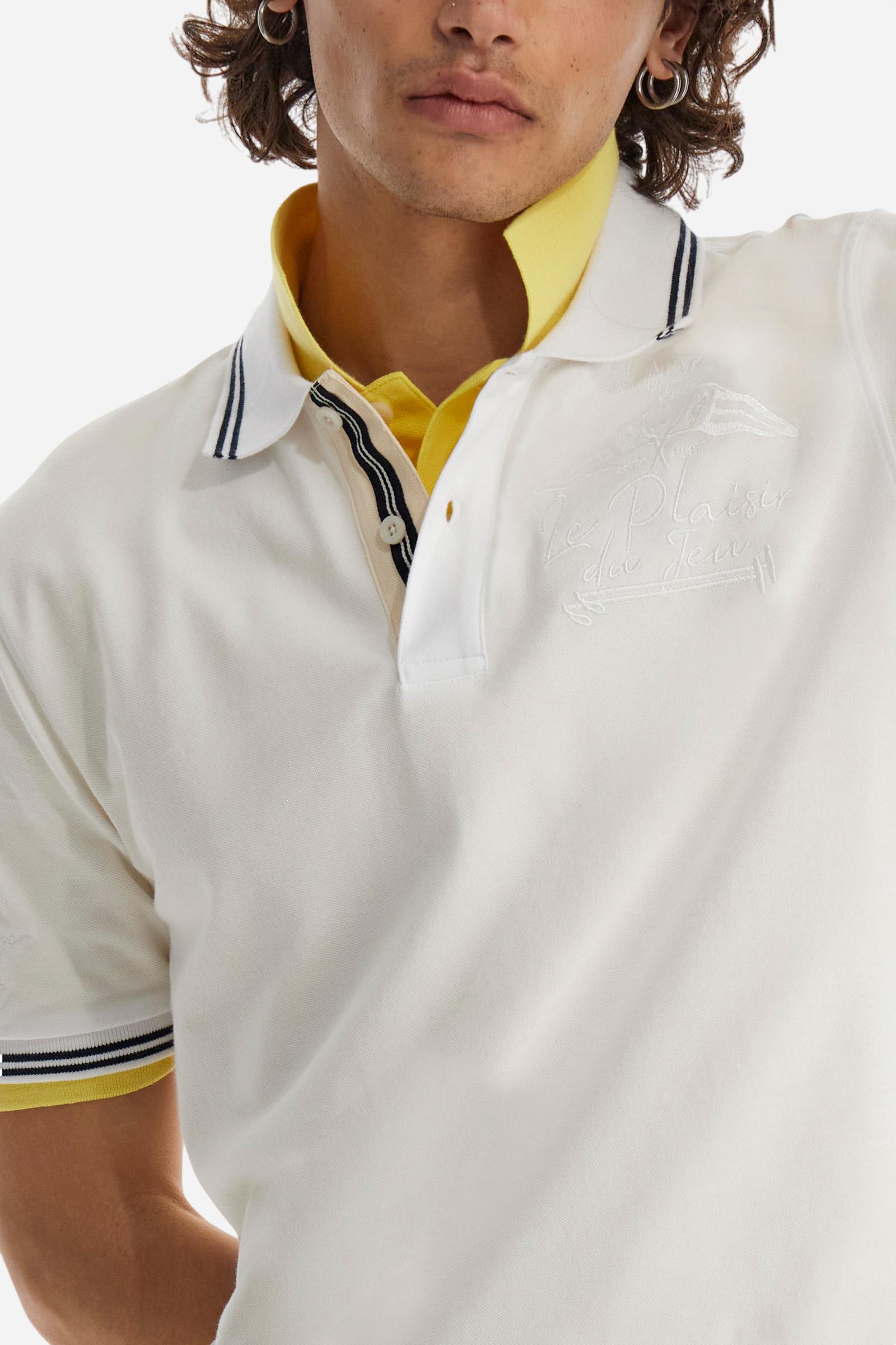Men's plain short-sleeved polo shirt made from stretch piqué. Two-button fastening. The collar and cuffs are made from two-tone striped ribbed fabric. The inside of the collar and placket feature contrasting fabrics and colours. There is a two-tone striped band around the inside of the collar. The right sleeve and chest are embroidered in tone-on-tone thread. A logo is embroidered on the left sleeve, also using tone-on-tone thread. Regular fit. The model is wearing a size L. - Optic White