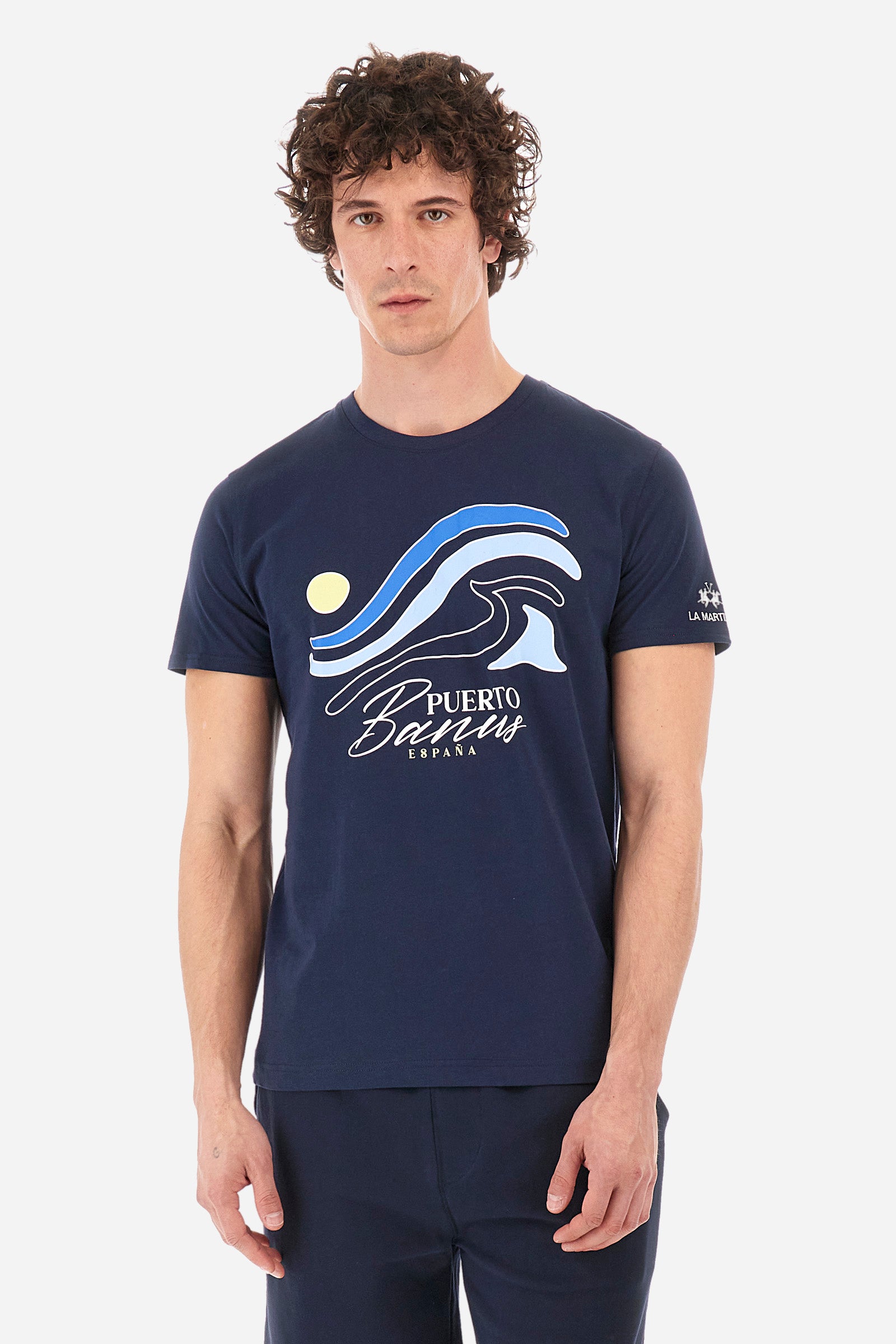 Men's short-sleeved T-shirt with a crew neck in a single colour. Made of 100% cotton. On the front there are stylised waves and the words "Puerto Banus España". A logo and the lettering "La Martina" are embroidered on one of the sleeves. Regular fit. The model wears a size L. - Navy