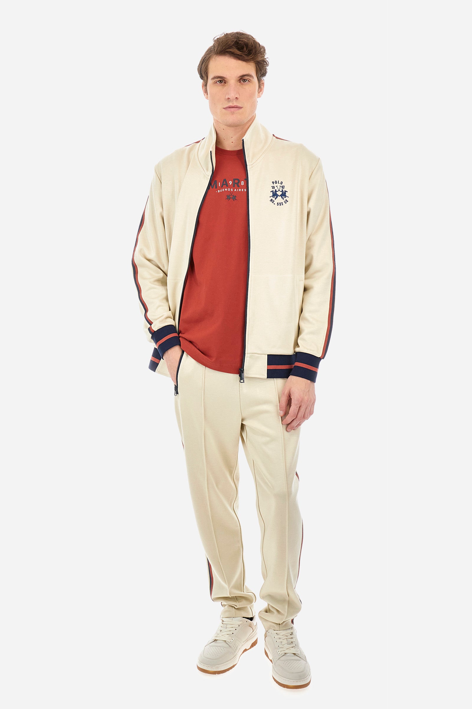 Men's single-colour jogging bottoms in a sweat fabric from the Polo Academy line, with contrasting details. Made of synthetic material. Drawstring waist. Double back pocket with contrasting zip fastening. Another pocket is present on the back. With coloured stripes on the sides of the trousers. The logo is sewn on the back pocket. The fit is regular. The model wears a size L. - Bone White