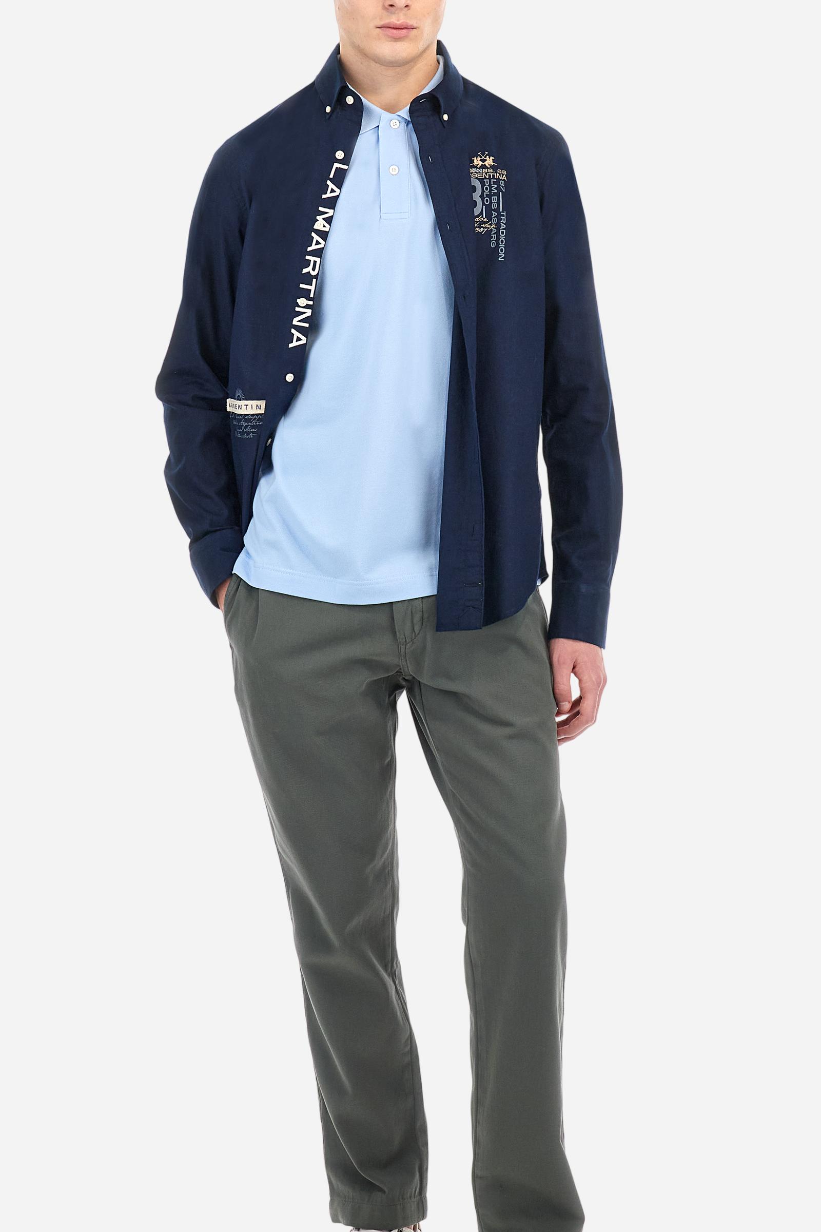 Men's plain long-sleeved shirt made from cotton and linen canvas. Featuring a button-down collar and sleeve openings embellished with contrasting fabric details. The graphic on the chest, over the heart, is created using a combination of embroidery and printing techniques to add a distinctive touch. On the side, at the front, there is a ribbon embroidered with the word Argentina, topped with a print. Regular fit. The model is wearing a size L. - Navy