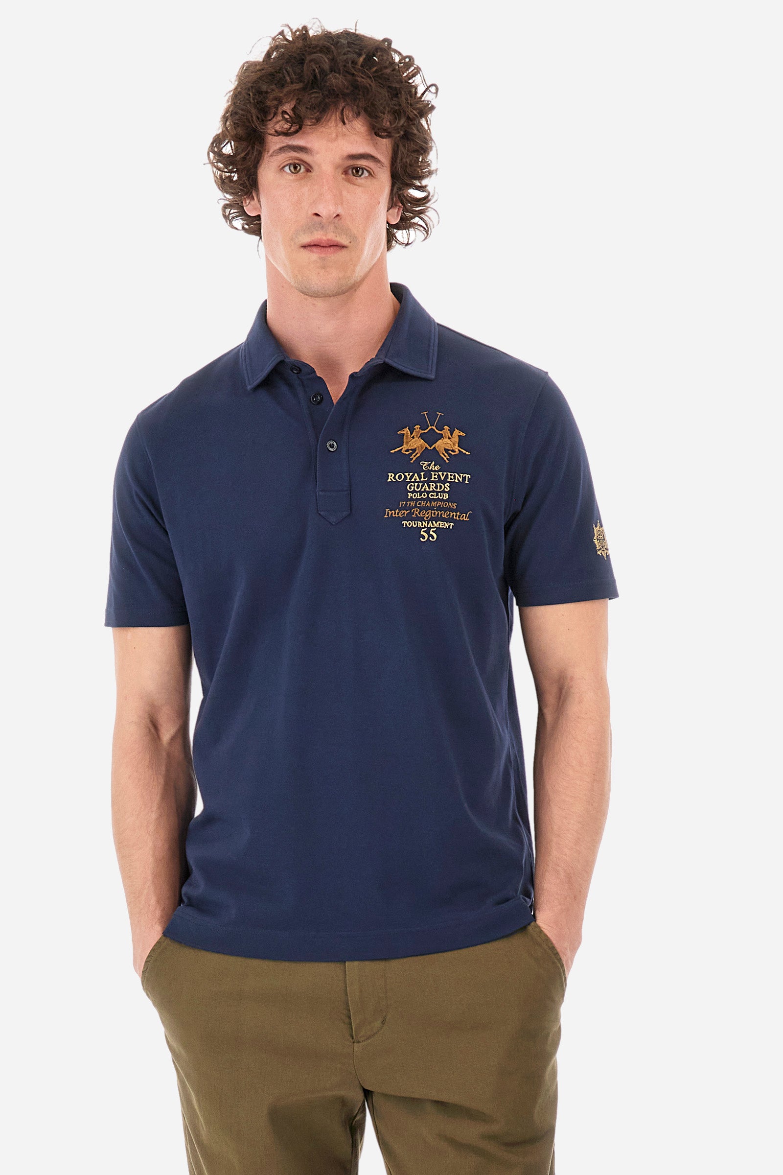 Men's short-sleeved single-colour polo shirt in elasticated cotton. Two-button fastening. Pointed collar. On the front we find copper-coloured lettering and a large logo. On one of the sleeves there is a symbol representing the Guards line. The fit is regular. The model wears a size L. - Navy