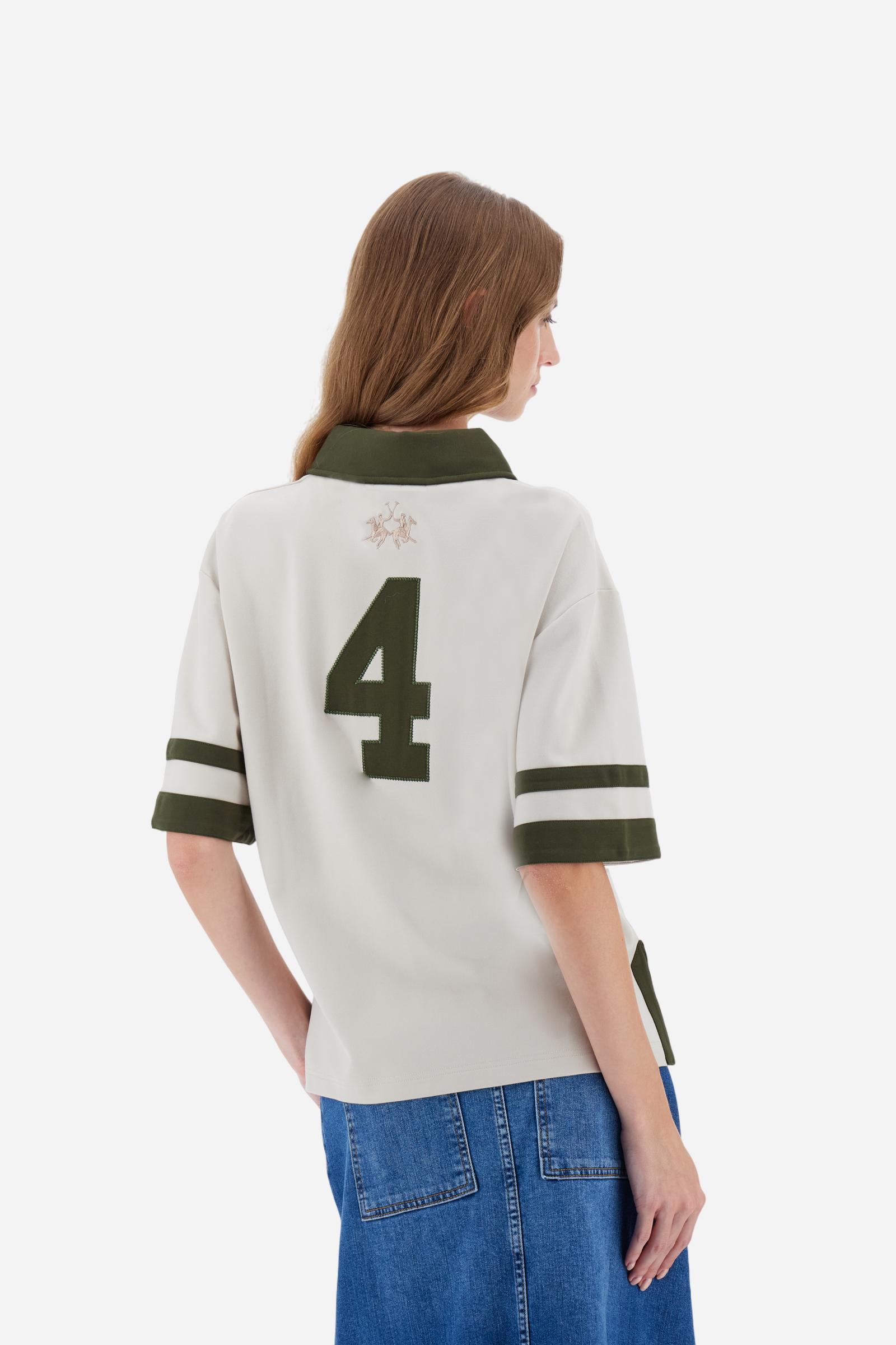 Women’s short-sleeve polo shirt in high-quality solid-colour viscose blend interlock. Classic collar with deep three-button placket, contrast fabric details on body and sleeves. Large embroidered logo on the back. Boxy, straight fit at the hips for a modern and comfortable silhouette. The model wears size L. - Creme Brulè/Kombu Gr