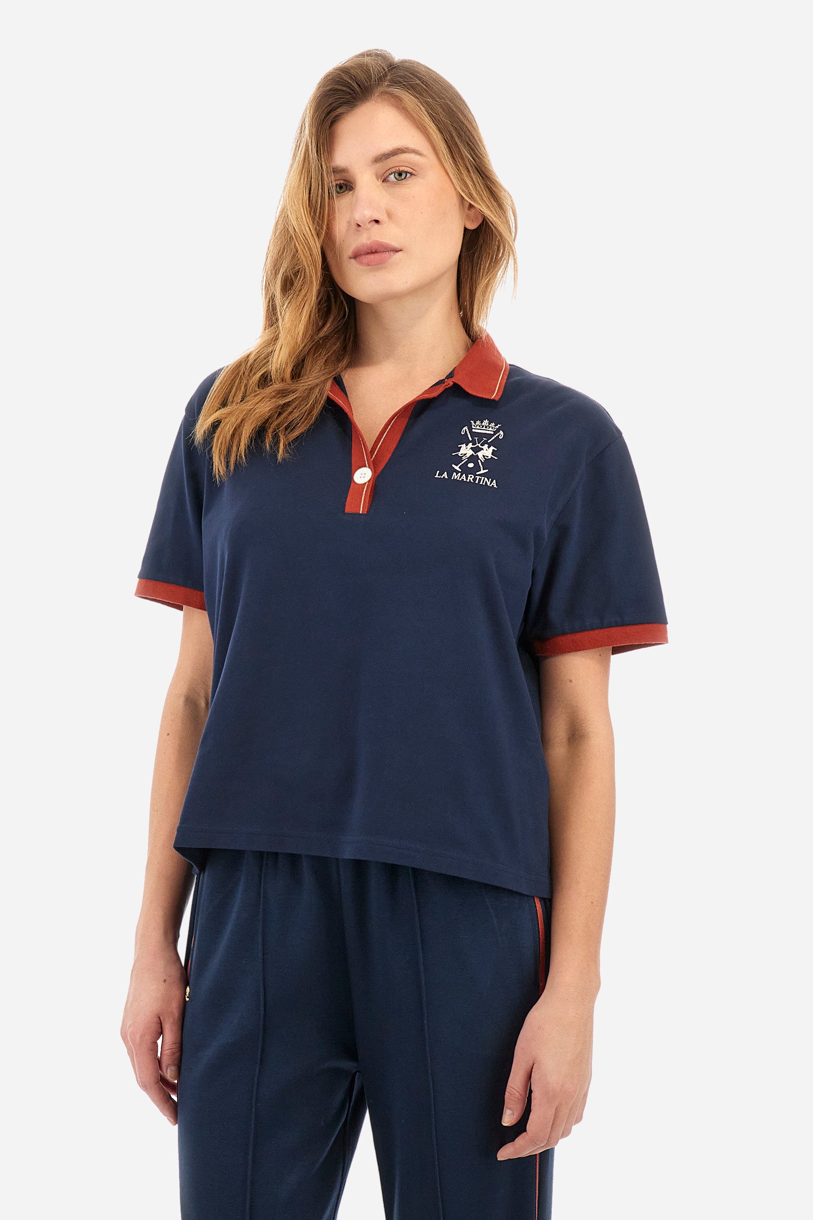 Women’s polo with short sleeves in solid color with contrasting details of the Academy Polo line. Made of stretch cotton. V-neck and armhole hem in contrasting shades. Single button closure. Ribbed neckline, collar and armhole. On the back is sewn the name and logo of the brand. On the back there is a metal plate with the logo applied on a colored strip. The fit is regular. The model wears a size 2. - Navy