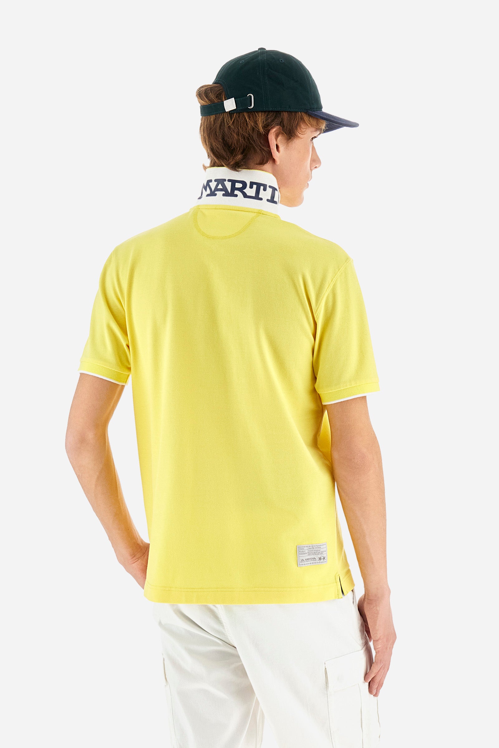 Men's plain short-sleeved polo shirt made from stretch piqué. Featuring a two-button fastening and a ribbon on the inside collar in contrasting coloured grosgrain. The collar and cuffs are in matching rib knit, with the undercollar also in rib knit but in a contrasting colour. The large logo is embroidered on the chest, left side with contrasting coloured thread. The undercollar features a print of the La Martina lettering in a contrasting colour. Regular fit. The model is wearing a size L. - Aurora