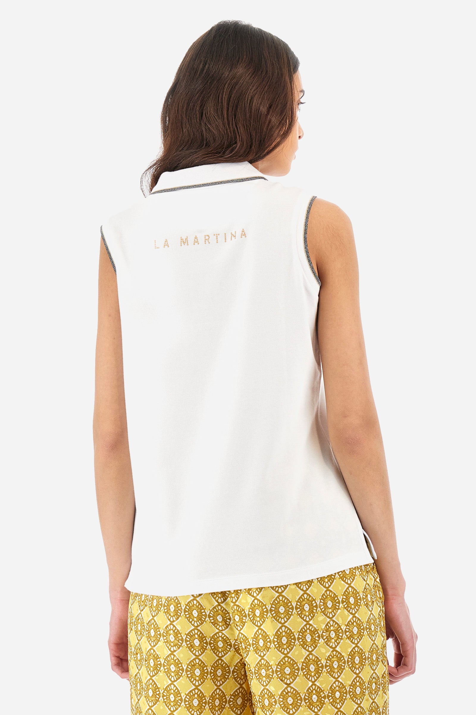 Women’s sleeveless polo shirt in solid color, made of stretch cotton. V-neck and 2 button closure. Collar and crew sleeves profiled and ribbed. Side slits. On the back there is the inscription "La Martina" composed of small rhinestones. The logo is present on the front. The fit is regular. The model wears a size 2 . - Optic White