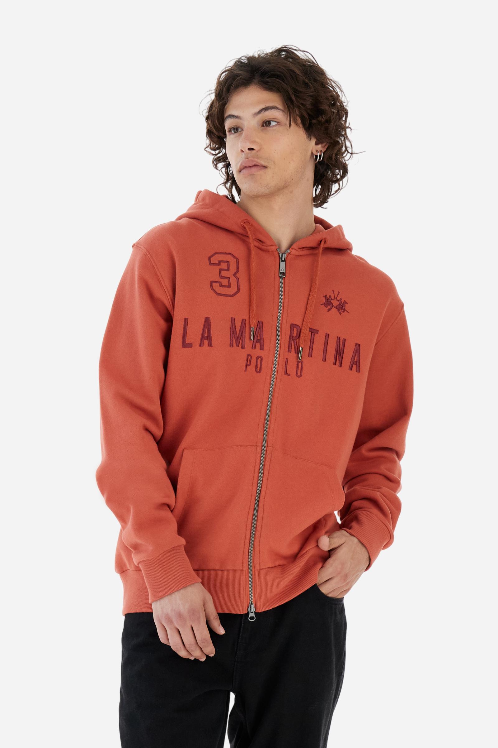 Men's long-sleeved hoodie in solid colour, made from soft 100% cotton fleece with a velvety touch. The model features a customised front zip and an adjustable hood with drawstring. Hem and cuffs in tone-on-tone rib. Iconic brand graphics stand out on the chest, embroidered with numbers and lettering. Regular fit ensuring comfort and freedom of movement. Model wears size L. - Burnt Ochre