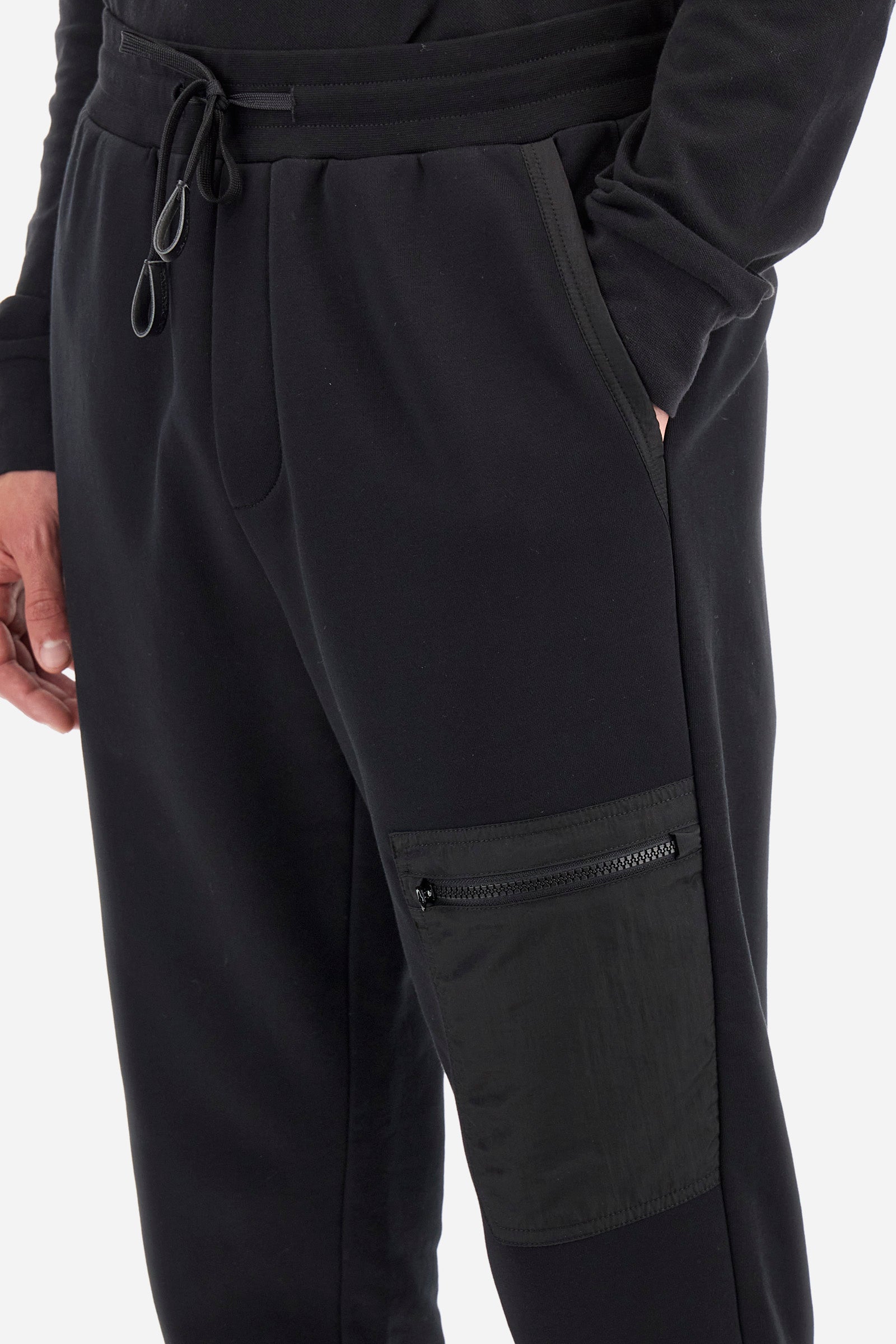 Men's plain jogging bottoms, made from a cotton blend. Drawstring waist and cuffs. Double front pocket. There is an additional zipped pocket on the front. The logo appears on an appliquéd plaque the back. Regular fit. The model is wearing a size L. - Black