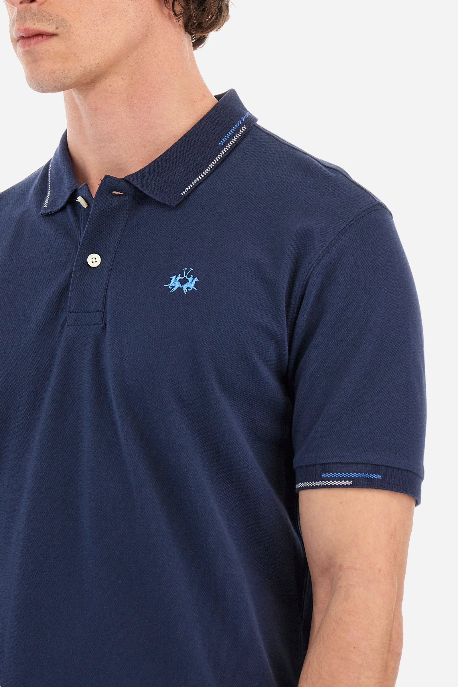 Men's single-colour short-sleeved polo in elasticated cotton. Two-button fastening. Ribbed collar and armholes with a stripe in different shades. Featuring a small logo embroidered on the chest. The fit is regular. The model wears a size L. - Navy
