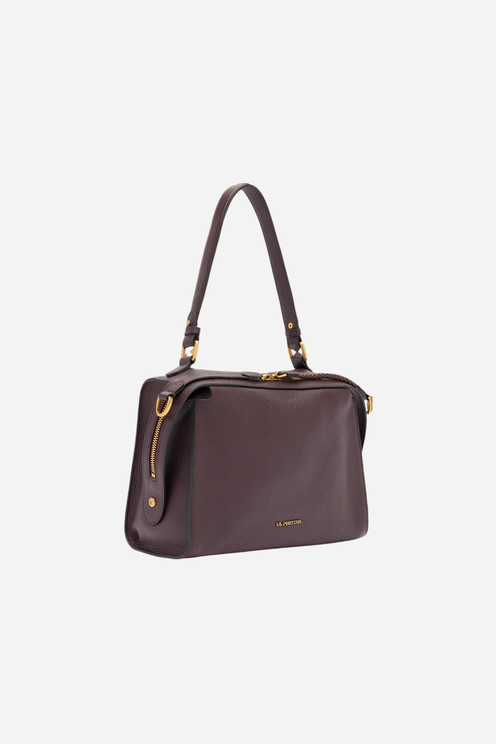 Compact shoulder bag made of high-quality full-grain leather. The double side zip with long leather pullers creates both functional and decorative detail. The slightly trapeze silhouette and the gold metal logo plaque define its distinctive and elegant character. Dimensions:28 x 22 x 12 - WINE