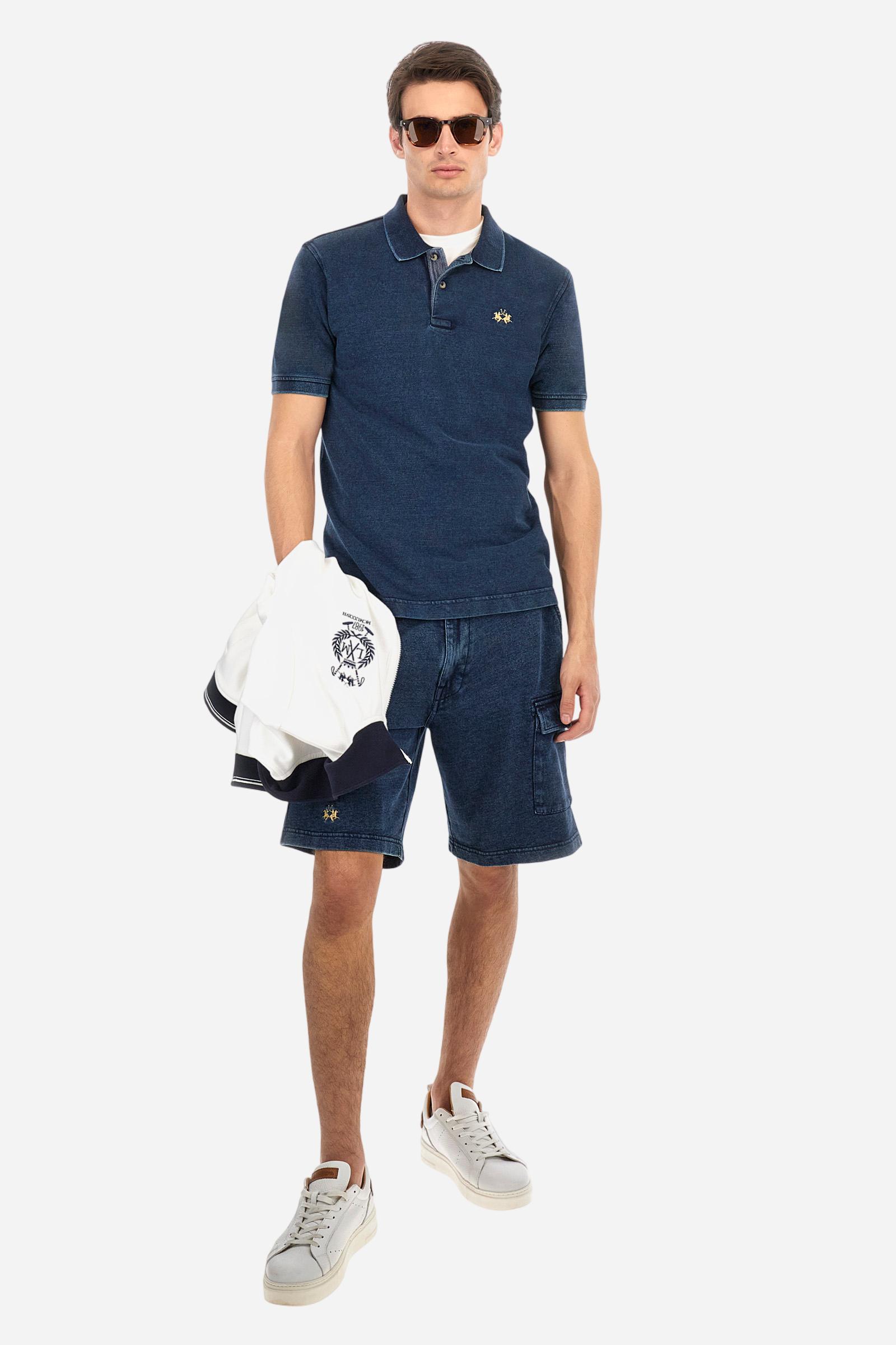 Men's short-sleeved polo shirt made of 100% cotton indigo pique. Fastens with two buttons. The collar and cuffs are folded and are made of ribbed fabric. Garment treated with enzyme washing, which gives the faded and lived-in look typical of denim. The contrasting embroidered logo is present on the left side of the chest. Regular fit. The model is wearing a size L. - Dark Indigo Denim