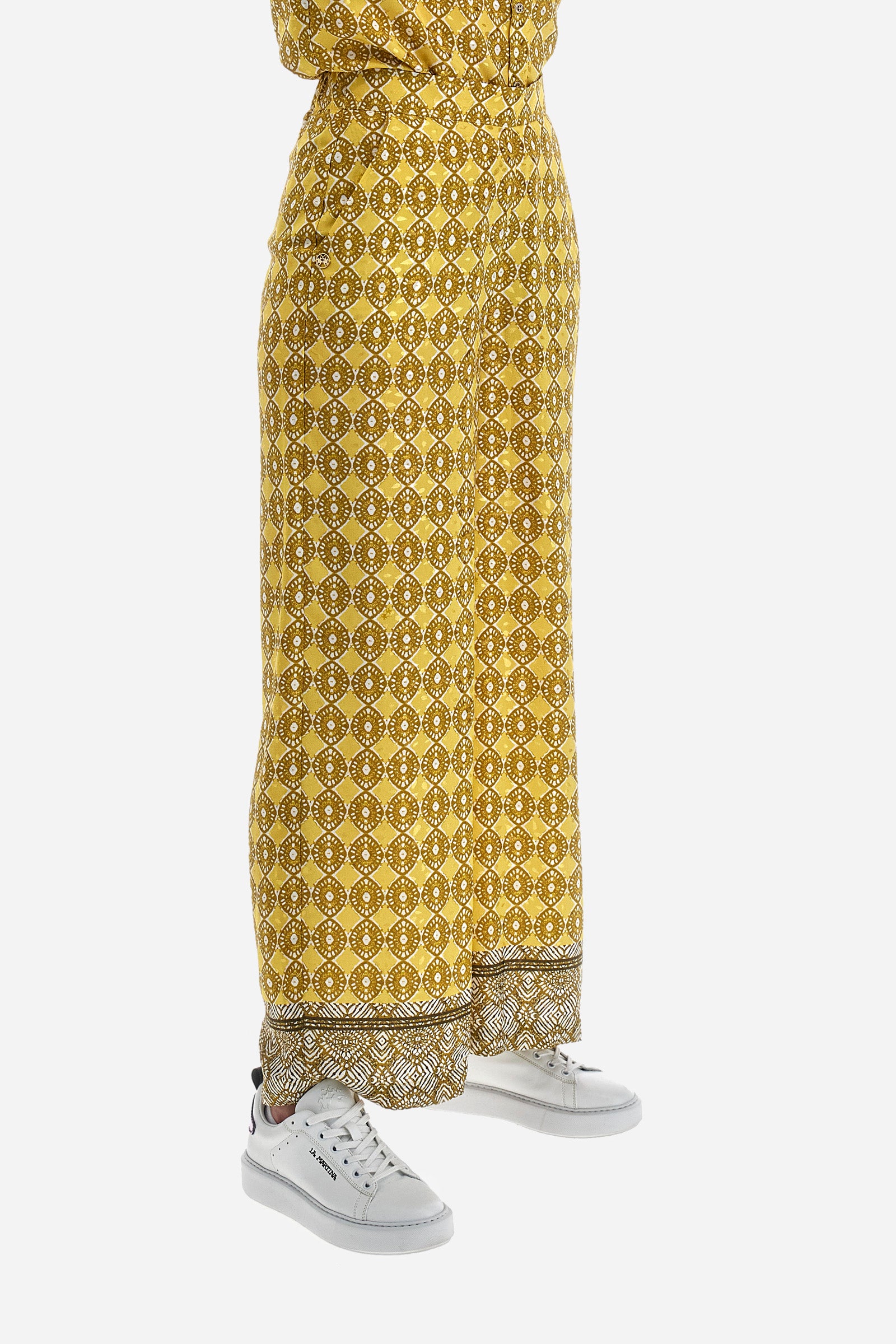 Women's palazzo trousers with geometric prints, made in a synthetic fabric. Elasticated waistband. There are two open front pockets. A metal plate with the logo is sewn on the front. The fit is regular. The model wears a size 2. - Goldfinch/Arrow/Whit