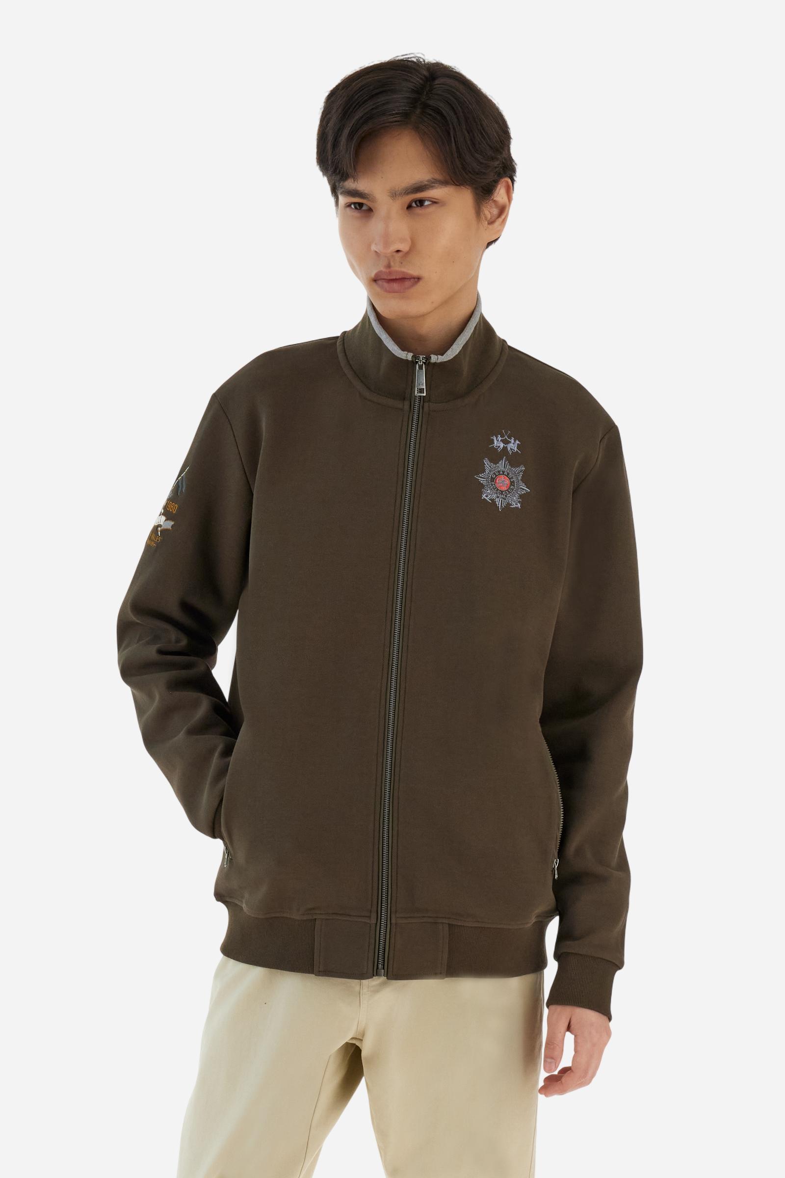 Men's long-sleeved, full-zip solid colour sweatshirt. Made of stretch cotton-blend piqué. Design with front opening fastened by a zip, high collar in two-tone ribbing. Solid colour ribbed cuffs and waistband. The small brand logo and Guards crest are embroidered in multi-coloured thread on the chest. On the right sleeve, there is another embroidery of a crest inspired by the British royal household. The regular fit silhouette is practical for everyday wear. The model is wearing a size L. - Java