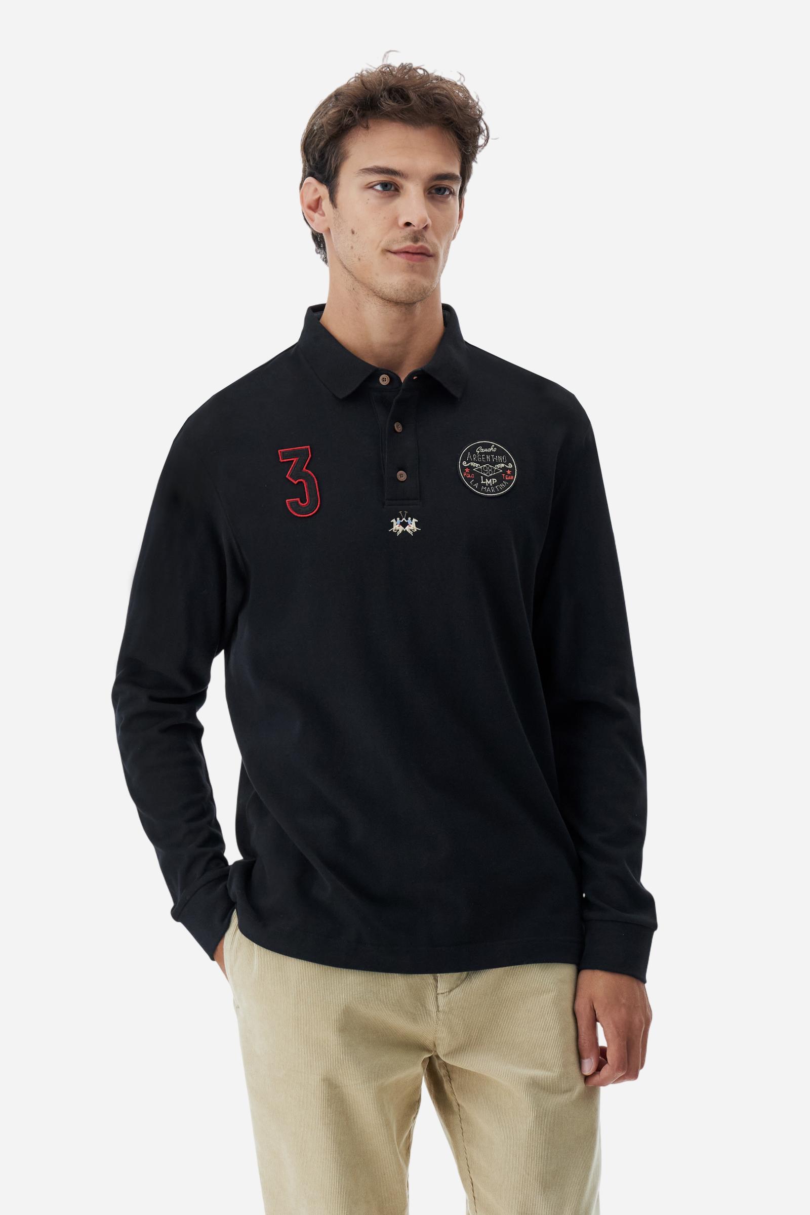 Long-sleeve polo shirt crafted from 100% high-quality cotton jersey. The velvety fabric offers a warm, cozy feel, perfect for cooler seasons. Ribbed collar and cuffs in matching tone, with a three-button personalized placket. A small multicolor embroidered logo sits below the opening, while tonal patches in different shapes and textures, inspired by Argentine culture and Gaucho tradition, decorate the chest and back. Classic regular fit. Model wears size L. - Black