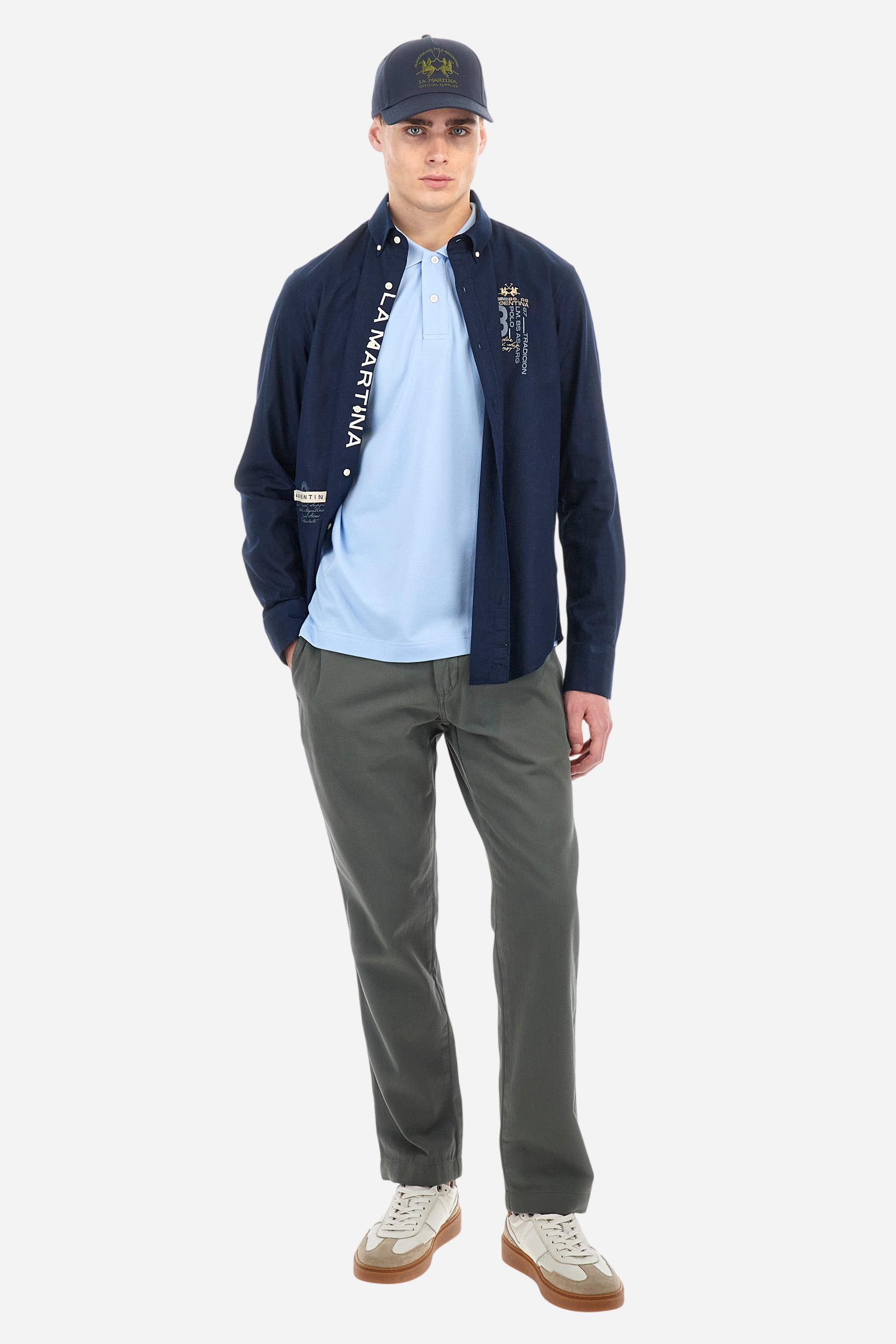 Men's plain short-sleeved polo shirt made from stretch piqué. Two-button fastening. The collar and cuffs are made from tone-on-tone ribbed fabric. Under the collar, there is a contrasting fabric panel with embroidered multicoloured lettering. The logo is embroidered on the left side of the chest in contrasting thread. Slim fit. The model is wearing a size L. - Blue Mist