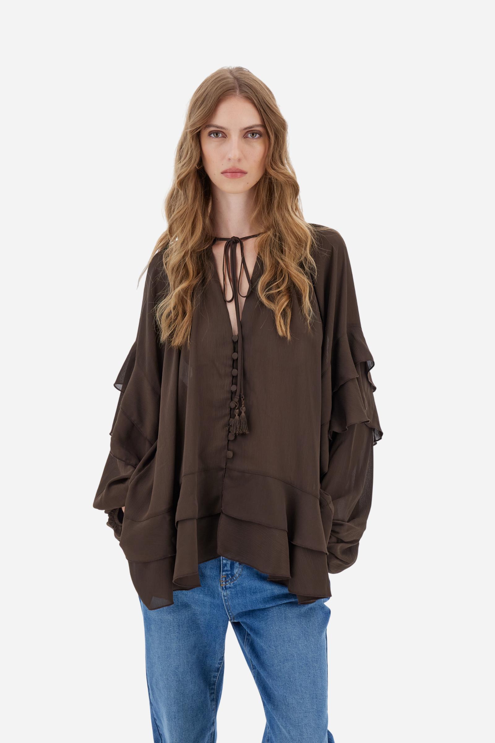 Women’s blouse with long sleeves in solid-colour chiffon with mandarin collar and V-neckline closed by ties and covered buttons. Loose fit with longer back and wide ruffles on sleeves and hem. The logo appears on a small golden metal plate applied to the front hem. The model wears size 2. - Java