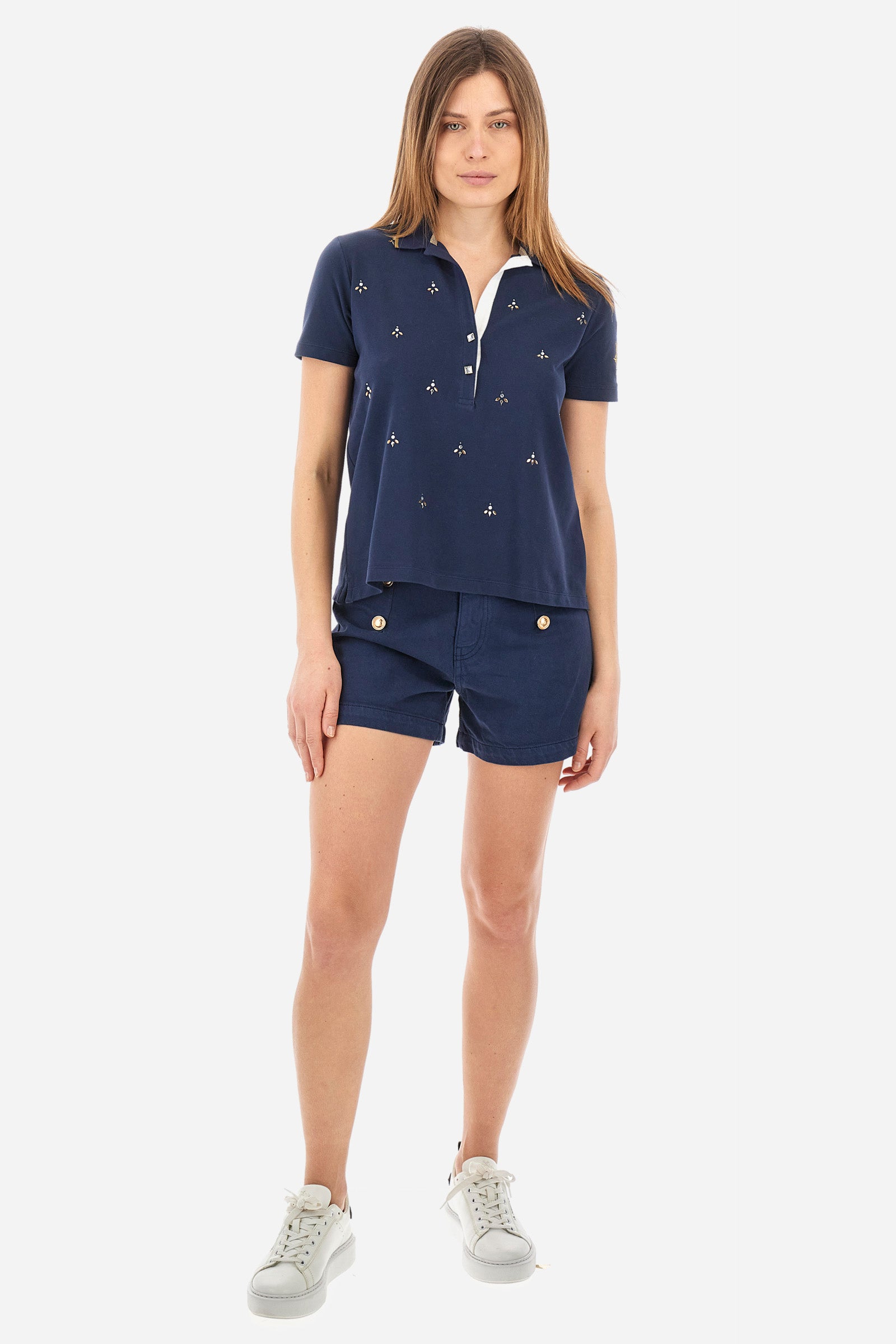 Women’s polo with short sleeves in solid color from the Guards line. Made of stretch cotton. V-neck and 2-button jewel closure. Ribbed collar. Side slits. Rhinestones of various shapes, sizes and colors were applied to the front. The logo and the characteristic symbol of the line are embroidered on a sleeve. The fit is regular. The model wears a size 2 . - Navy