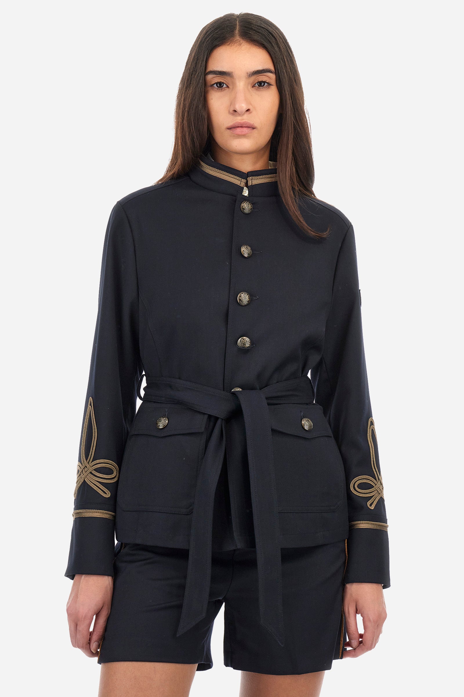 Women's long-sleeved Guards jacket, made from plain synthetic fabric. High neck. Button fastening. Decorations representing the Royal Guards line appear on the sleeves. Double pocket on the front, fastened with buttons. Belt loops at the waist. Regular fit. The model is wearing a size 42. - Navy