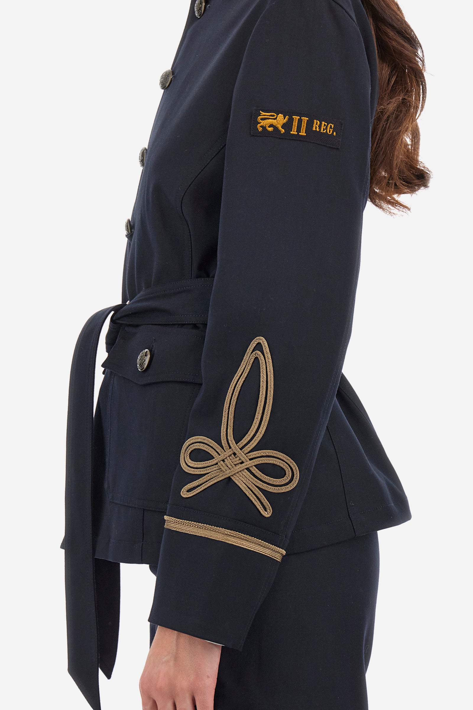 Women's long-sleeved Guards jacket, made from plain synthetic fabric. High neck. Button fastening. Decorations representing the Royal Guards line appear on the sleeves. Double pocket on the front, fastened with buttons. Belt loops at the waist. Regular fit. The model is wearing a size 42. - Navy