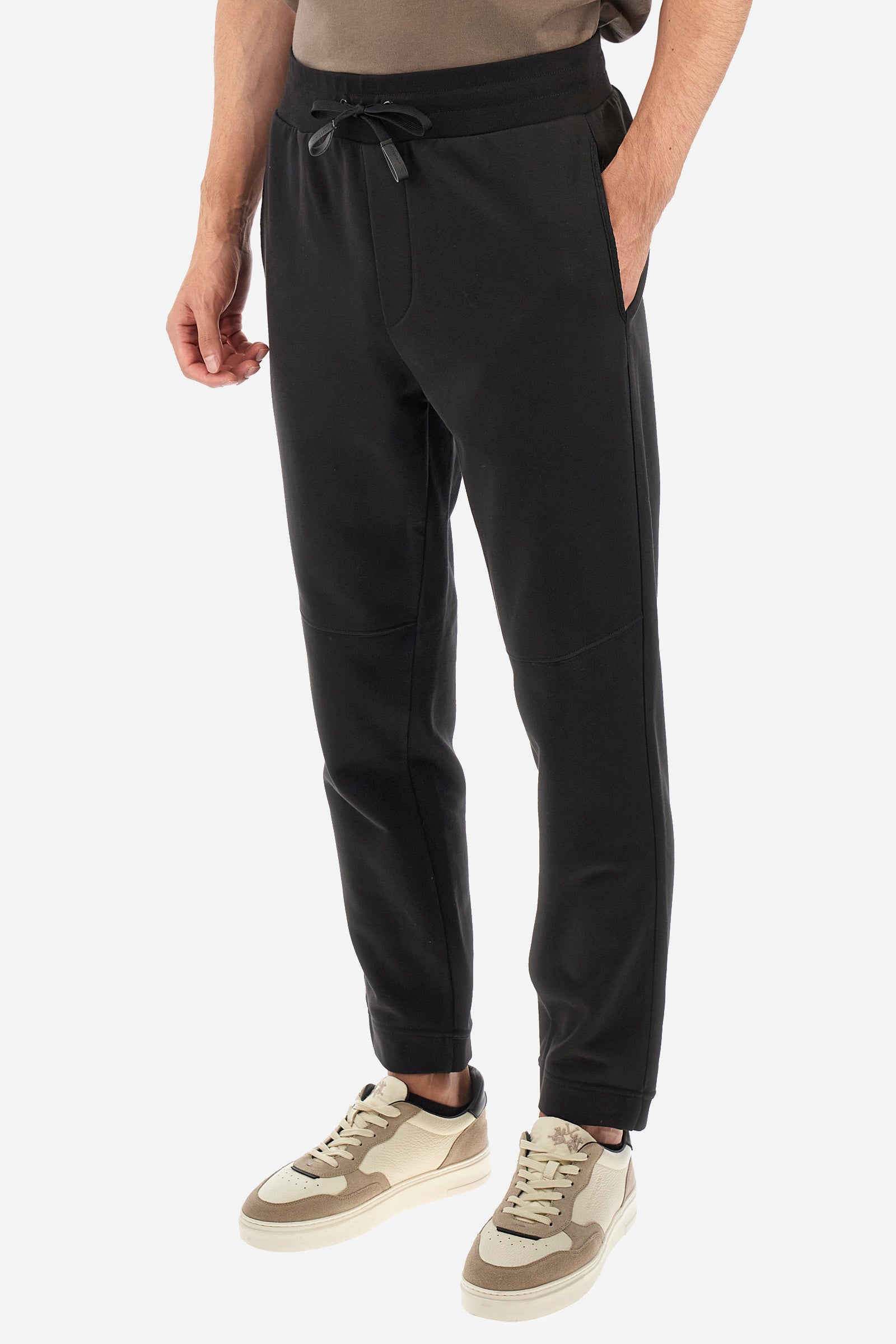 Men's single-colour jogging bottoms in a cotton sweat fabric. With a drawstring waist and double front pocket. With different shades at the bottom of the leg. On the back there is a pocket with a zip fastening featuring contrasting textures and colours. The logo is present on the tag sewn on the back pocket. The fit is regular. The model wears a size L. - Black