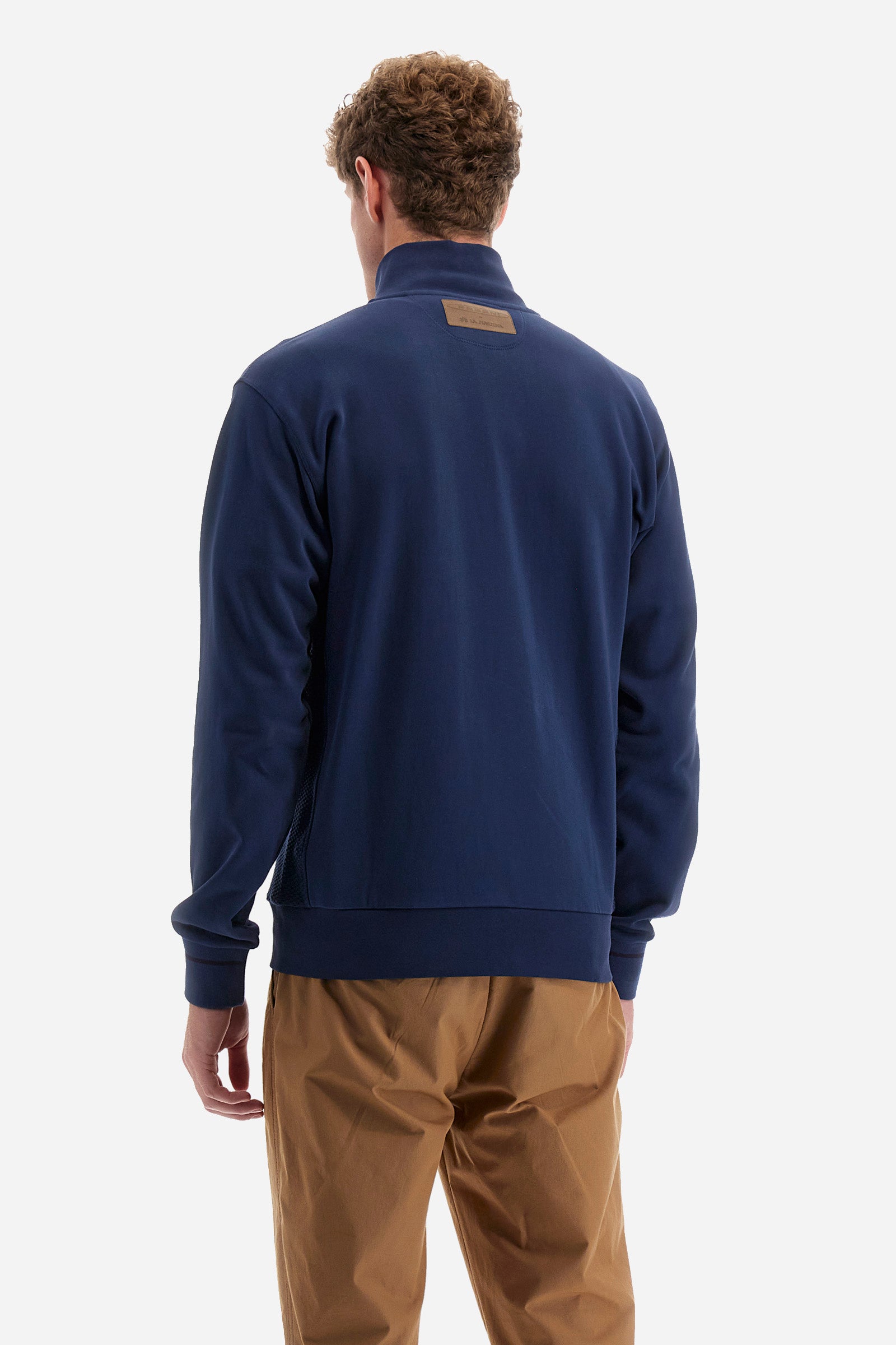 Single-colour long-sleeved men's sweatshirt with full zip fastening from the line in collaboration with Pagani. Made of 100% cotton. Mock neck, ribbed waistband and cuffs. Double back pocket. On the sides the garment has a different texture from the main part. There is lettering on the front, while a plate featuring the La Martina logo and the Pagani logo is sewn on the back. The fit is regular. The model wears a size L. - Ensign Blue