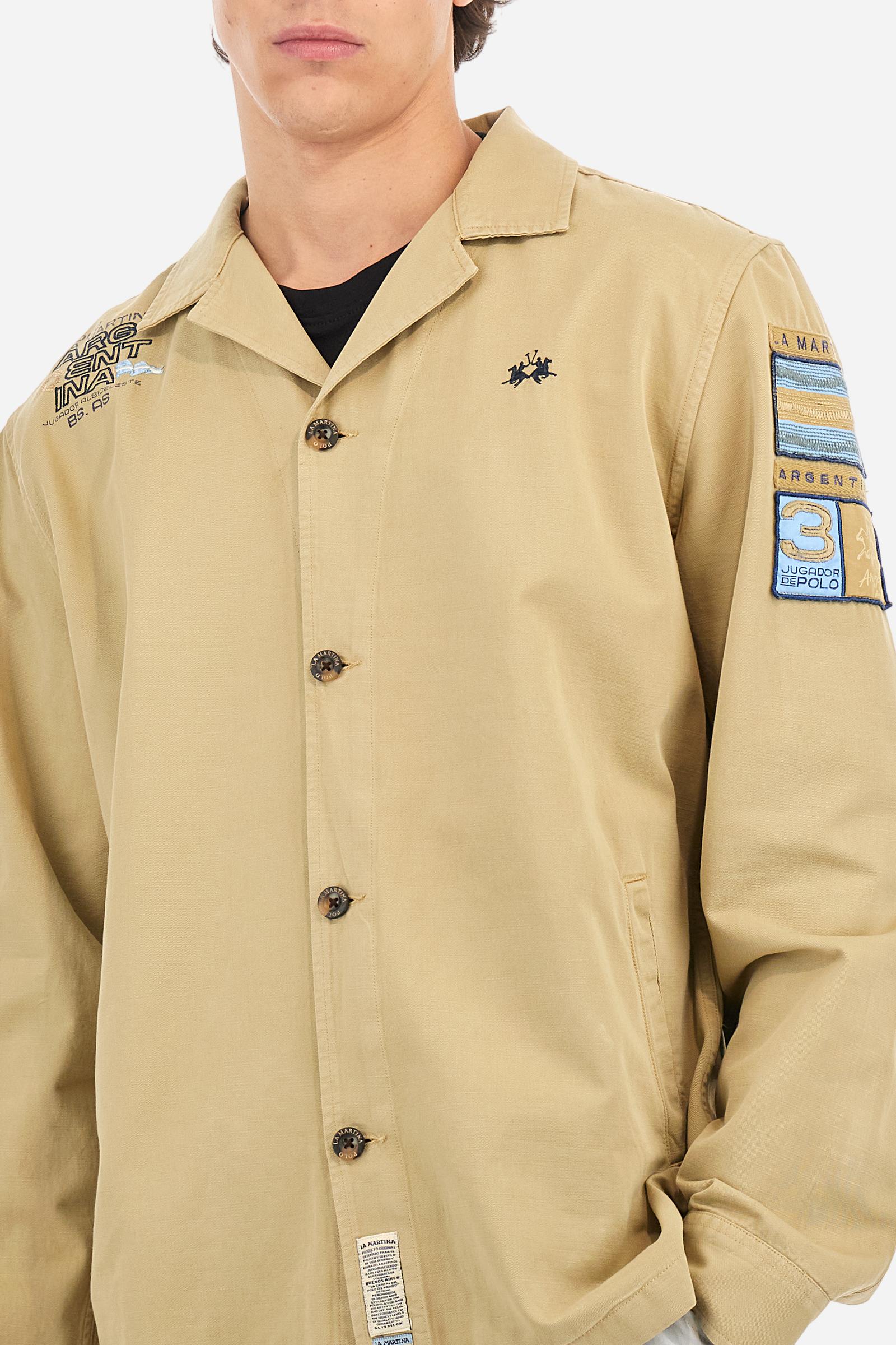 Men's single-colour long-sleeved overshirt made of 100% cotton slub twill. Bowling collar and jacket opening with inside placket, fastening with imitation horn buttons.On the shoulder and chest the embroidery is in tone with the garment, Argentina lettering embroidered on one shoulder. There are several patches applied on the left sleeve. A tone-on-tone logo is embroidered on the front. Regular fit. The model is wearing a size L. - Twill