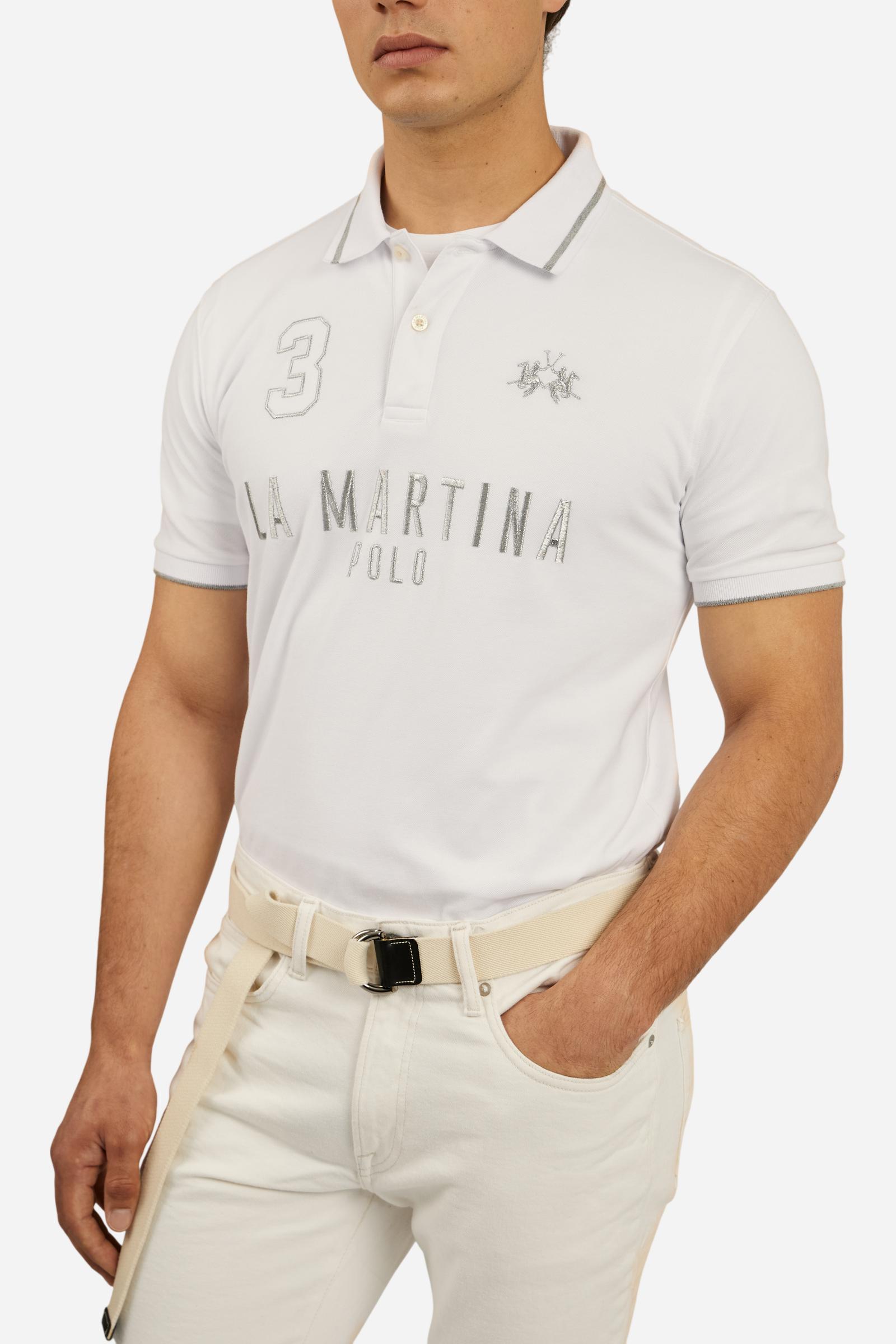 Men's plain short-sleeved polo shirt made from stretch piqué. Two-button fastening. The collar and cuffs are made from ribbed fabric with narrow contrasting trim at the bottom. The large La Martina Polo lettering on the chest is embroidered in contrasting thread. The number 3 patch appliquéd on the right side of the chest and the logo on the left side are also embroidered using contrasting thread. Regular fit. The model is wearing a size L. - Optic White