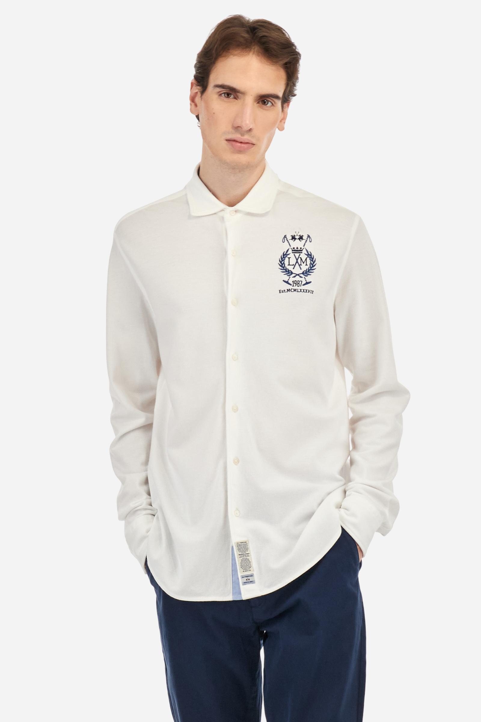 Men's plain long-sleeved shirt made from cotton piqué. It features an elegant spread collar and a seamless front opening, with no visible stitching. A graphic is embroidered on the chest, over the heart, in contrasting thread. Regular fit. The model is wearing a size L. - Optic White