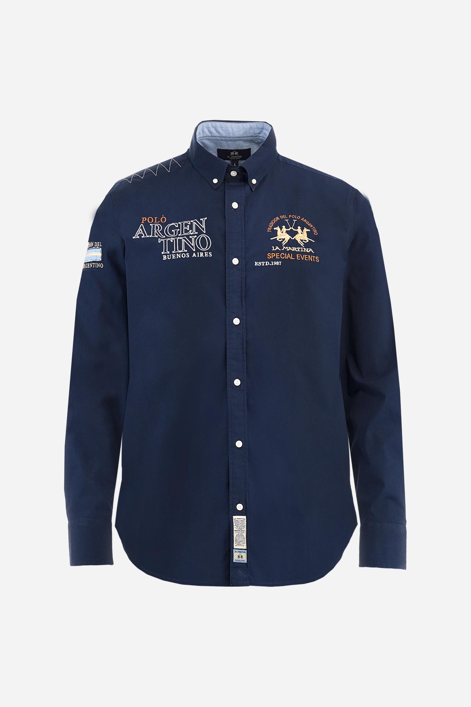 Men’s long-sleeved shirt made from stretch cotton poplin in solid color. Classic button placket with visible personalized buttons and button-down collar with contrasting inner details. Adorned with multiple embroidered graphics on the chest, sleeves, and back celebrating La Martina as the Official Supplier of Argentina. Regular, classic fit. The model wears size L. - Navy