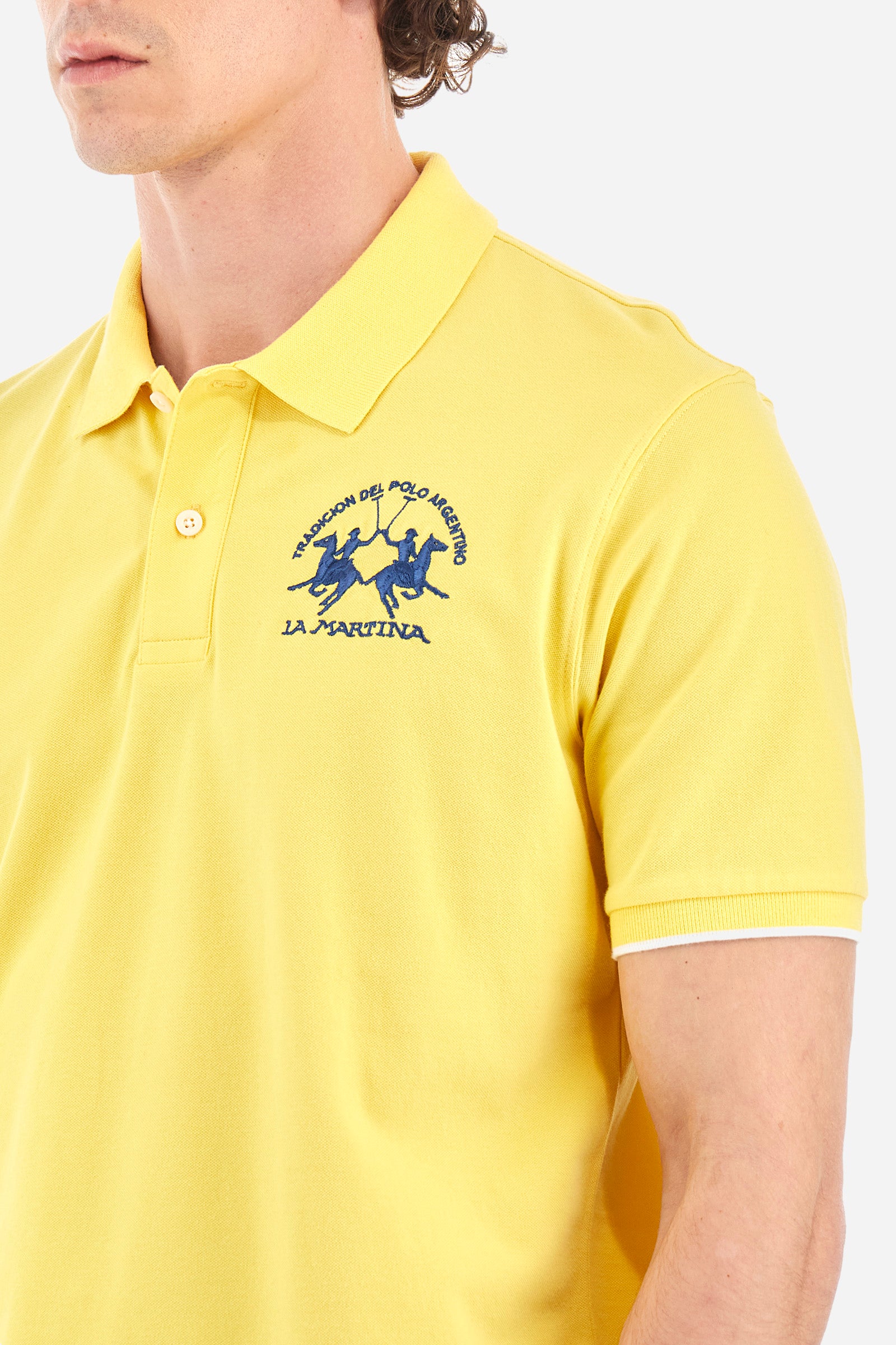 Men’s polo with short sleeves, regular fit. Made of stretch pique cotton. Classic model, with large embroidered logo in contrasting tone on the chest and profiled sleeve edges. The collar is accompanied by the writing La Martina, in contrasting tone. Ideal if worn with a denim collection. The model wears a size L. - Aspen Gold