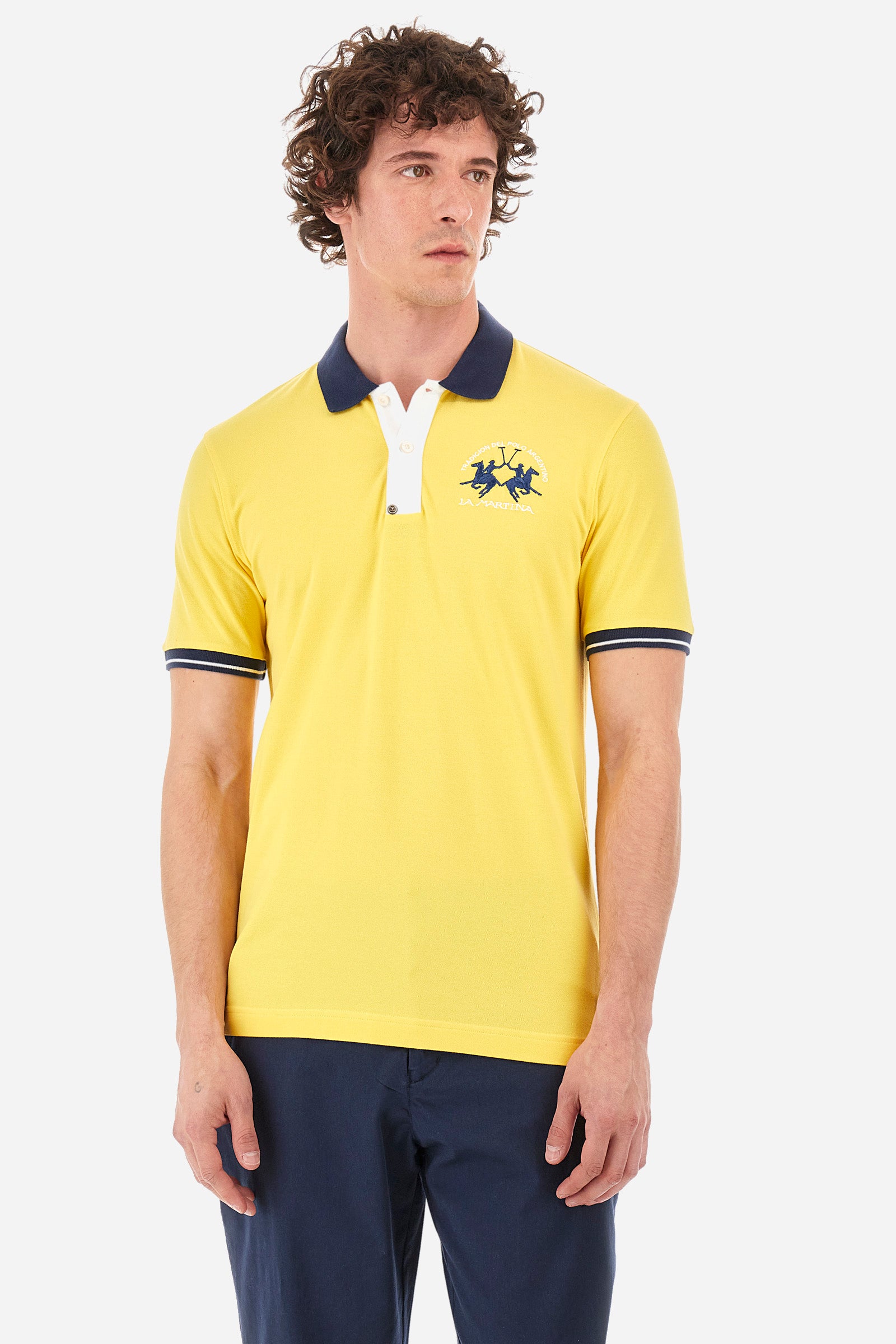 Men's single-colour short-sleeved polo in elasticated cotton. Fastens with two contrasting buttons. Ribbed collar and armholes in different shades. The "La Martina" lettering can be found under the collar. A large logo is embroidered on the chest. The fit is slim. The model wears a size L. - Aspen Gold