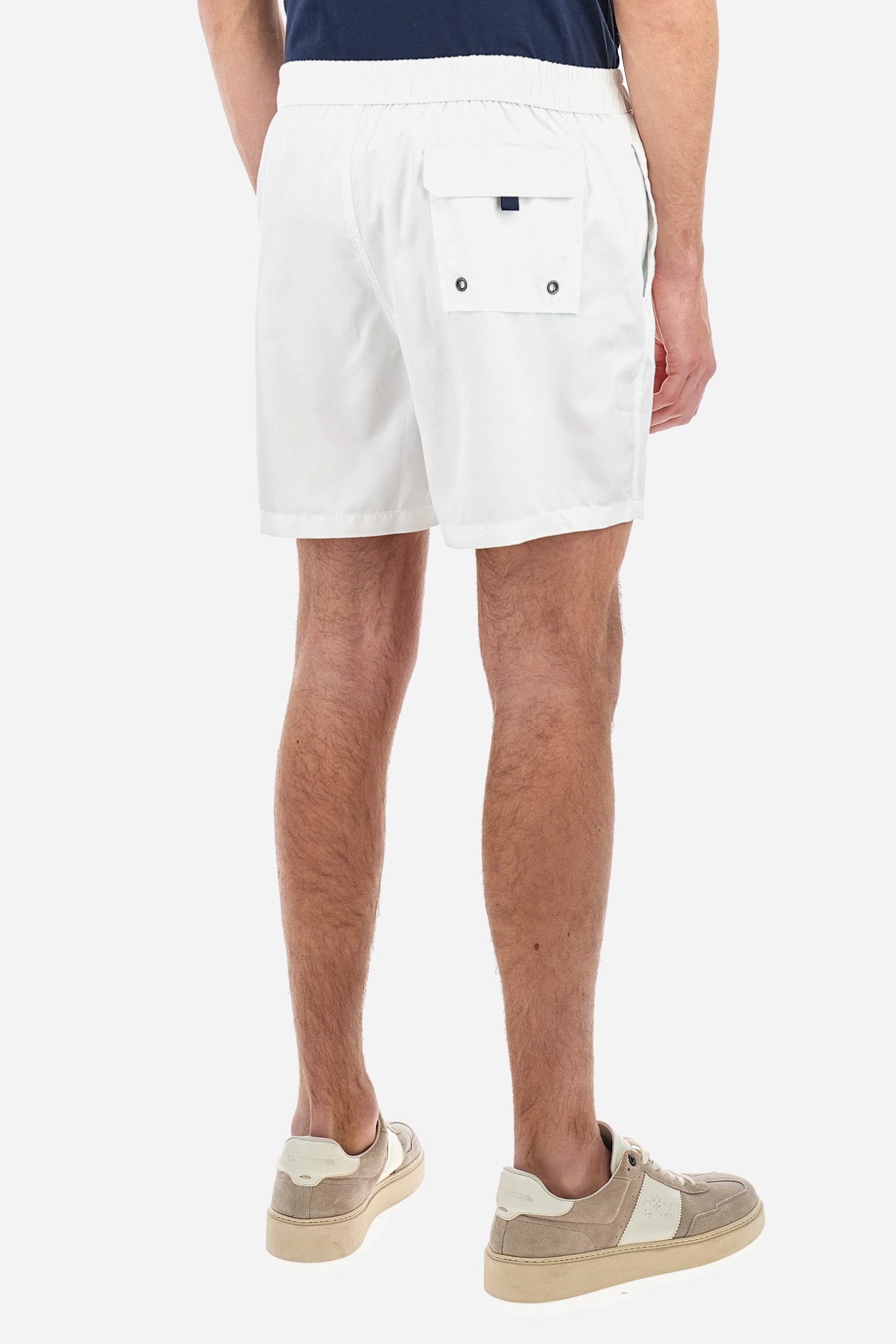 Plain men's swimming shorts made of nylon. Elastic waistband with a personalised drawstring for waist adjustment. On the inside of the shorts is an elasticated mesh brief. Double side pocket on the hips and patch pocket with flap on the back, on the right side only. The large logo is embroidered in a contrasting colour thread on the bottom of the left leg on the front. Regular fit. The model is wearing a size L. - Optic White