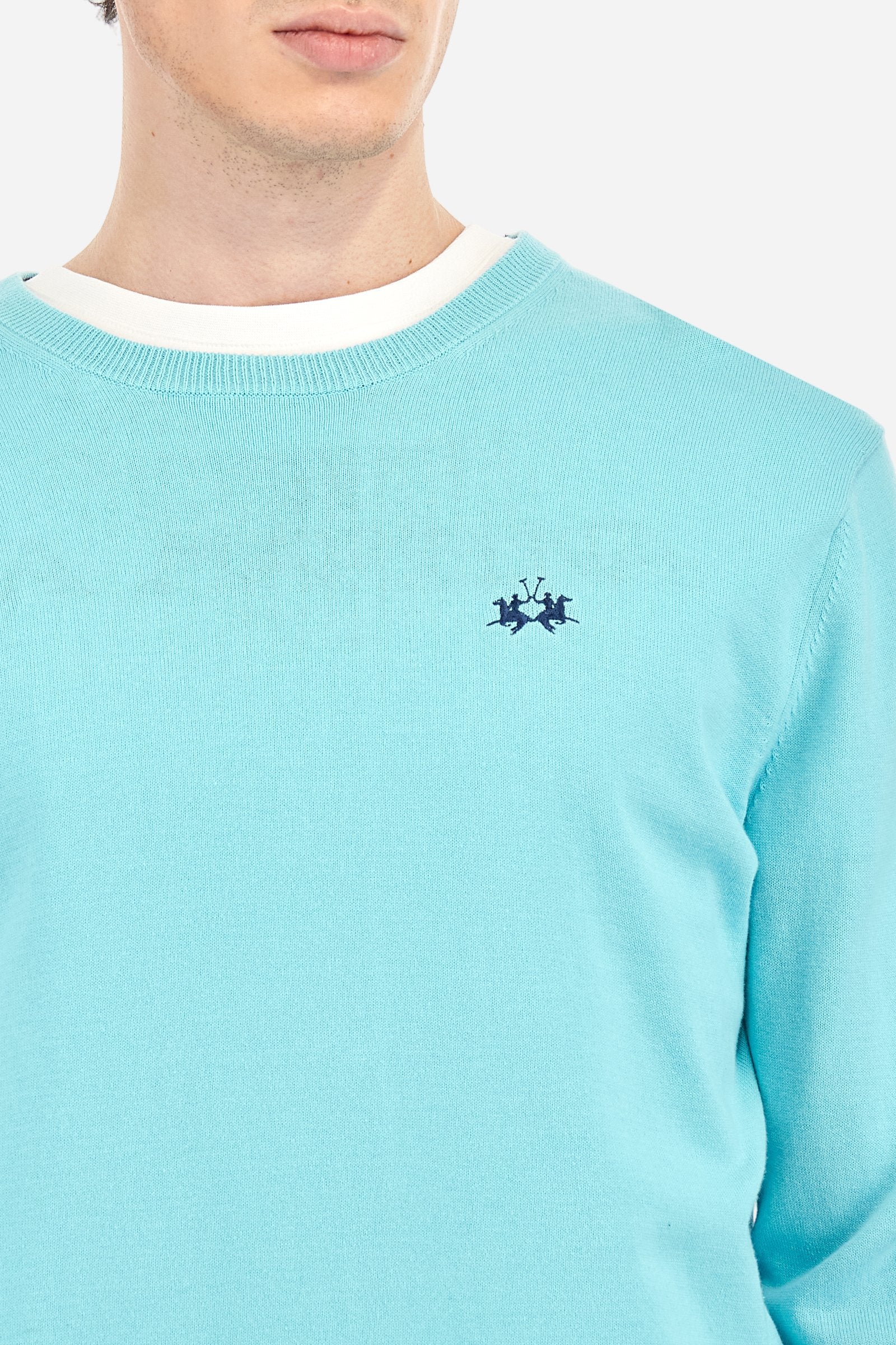 Men's plain long-sleeved pullover made of 100% combed cotton yarn. The collar is in two-tone ribbed knit: the exterior features the same tone as the jumper while the interior is in contrast. The cuffs and the band at the bottom are also made of ribbed knit. The cuffs also feature a contrasting stripe on the edge as a decorative motif. The logo is embroidered on the left side of the chest in contrasting thread. Regular fit. The model is wearing a size L. - Tanager Turquoise
