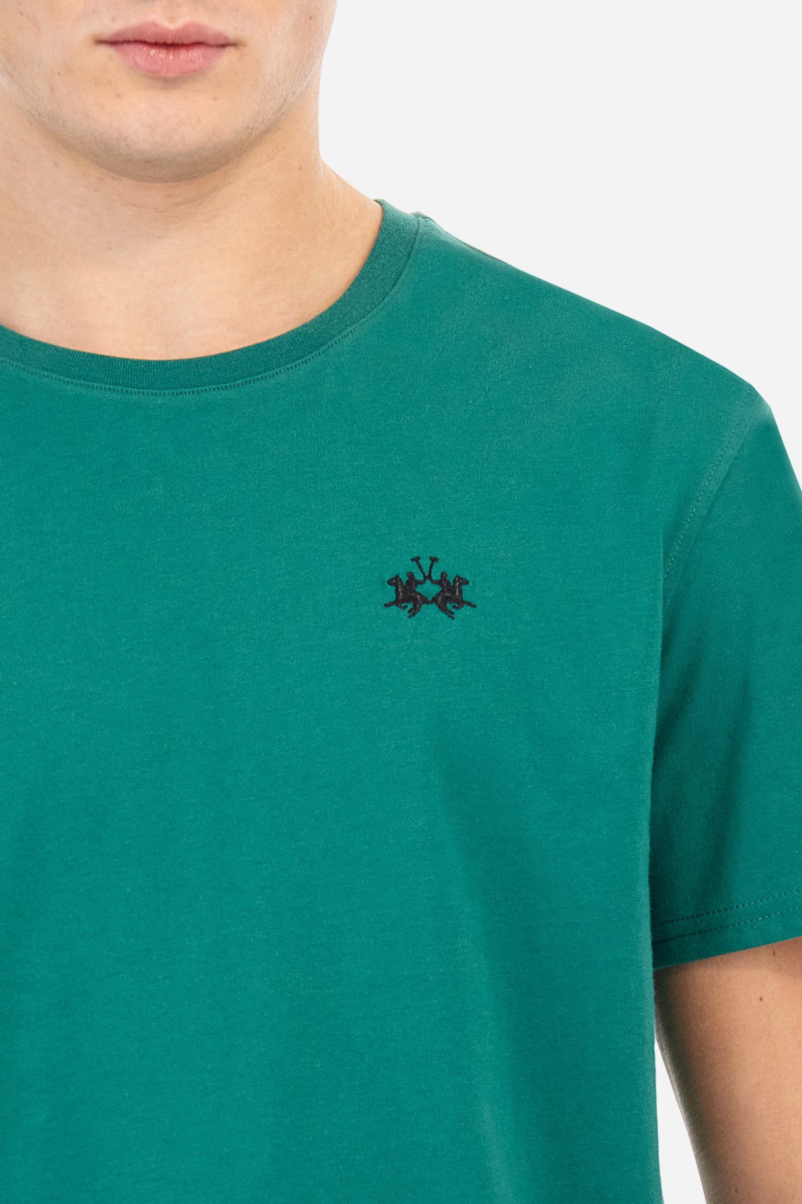 Men's short-sleeved crew-neck T-shirt in solid colour with embroidered logo in contrasting colour on the chest. Made of 100% cotton with a regular fit. It is perfect paired with Bermuda shorts or trousers for a casual and trendy look. Suitable for leisure time. The model is 187 cm tall and wears a size L. - Evergreen