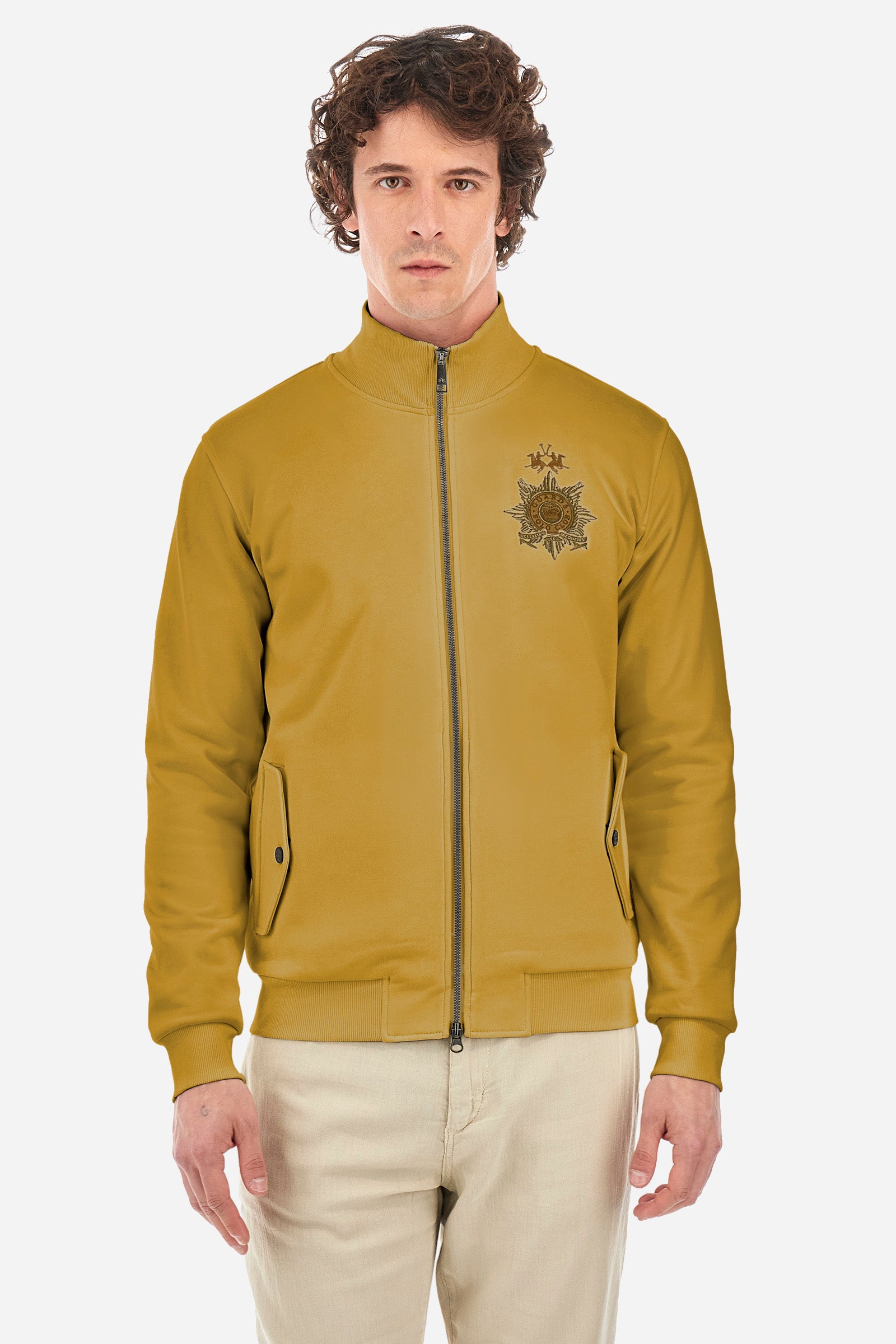 Men’s solid color long sleeve sweatshirt with full zip closure. Made of 100% cotton. High neck with drawstring, ribbed hem and cuffs. Double front pocket with button closure. Writing and large symbol on the chest identify the capsule collection. The fit is regular. The model wears a size L. - Arrowwood