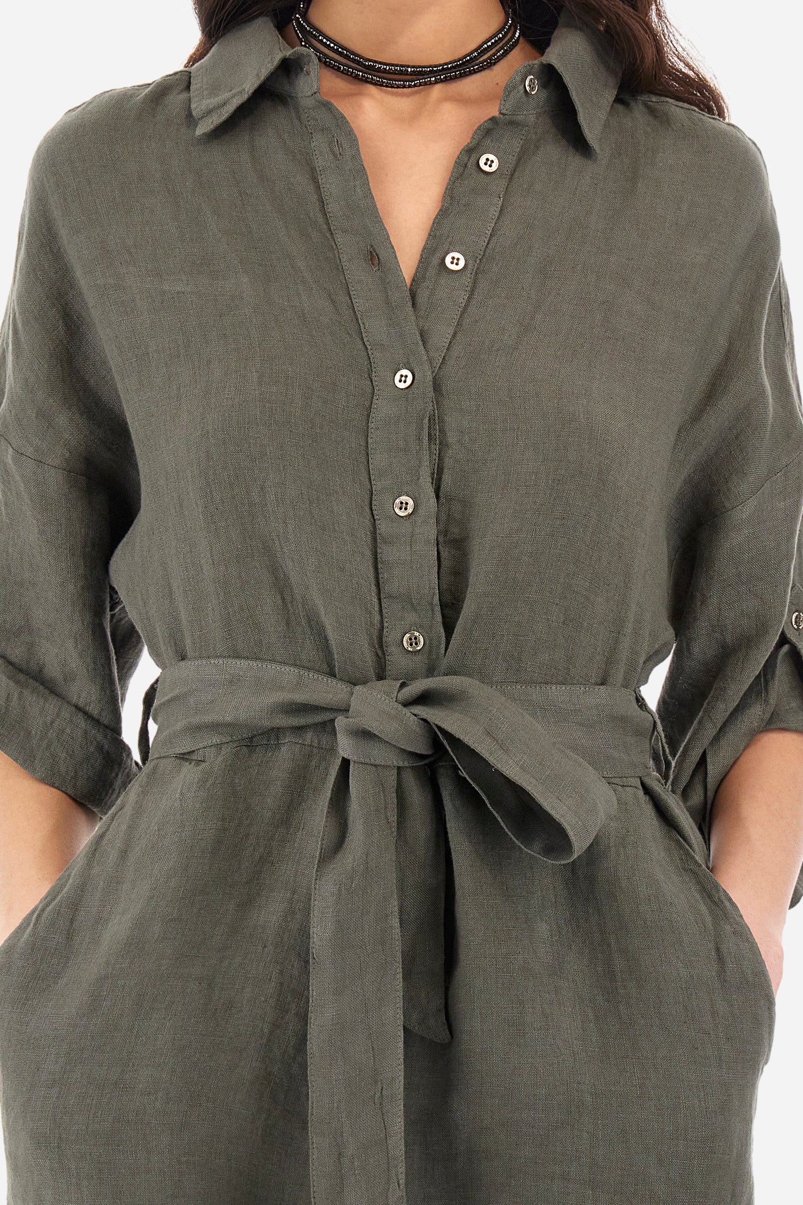 Women's one-piece playsuit with 3/4 sleeves with cuff and single-colour shorts. In 100% linen. French collar. With button fastening. Belt loops and fabric belt included. Featuring two front welt pockets and two back pockets. A logo and the lettering "La Martina" are embroidered on the back. The fit is regular. The model wears a size IT40. - Military Olive