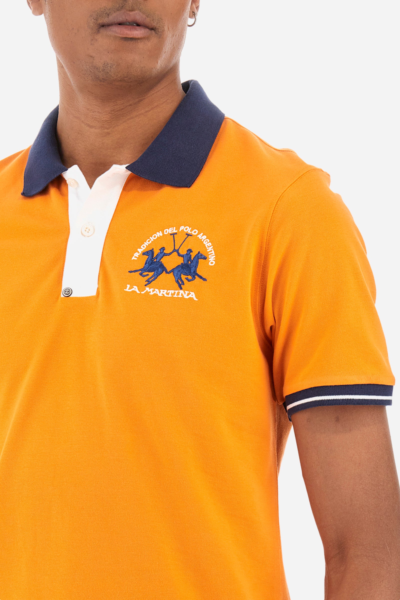 Men's single-colour short-sleeved polo in elasticated cotton. Fastens with two contrasting buttons. Ribbed collar and armholes in different shades. The "La Martina" lettering can be found under the collar. A large logo is embroidered on the chest. The fit is slim. The model wears a size L. - Celosia Orange
