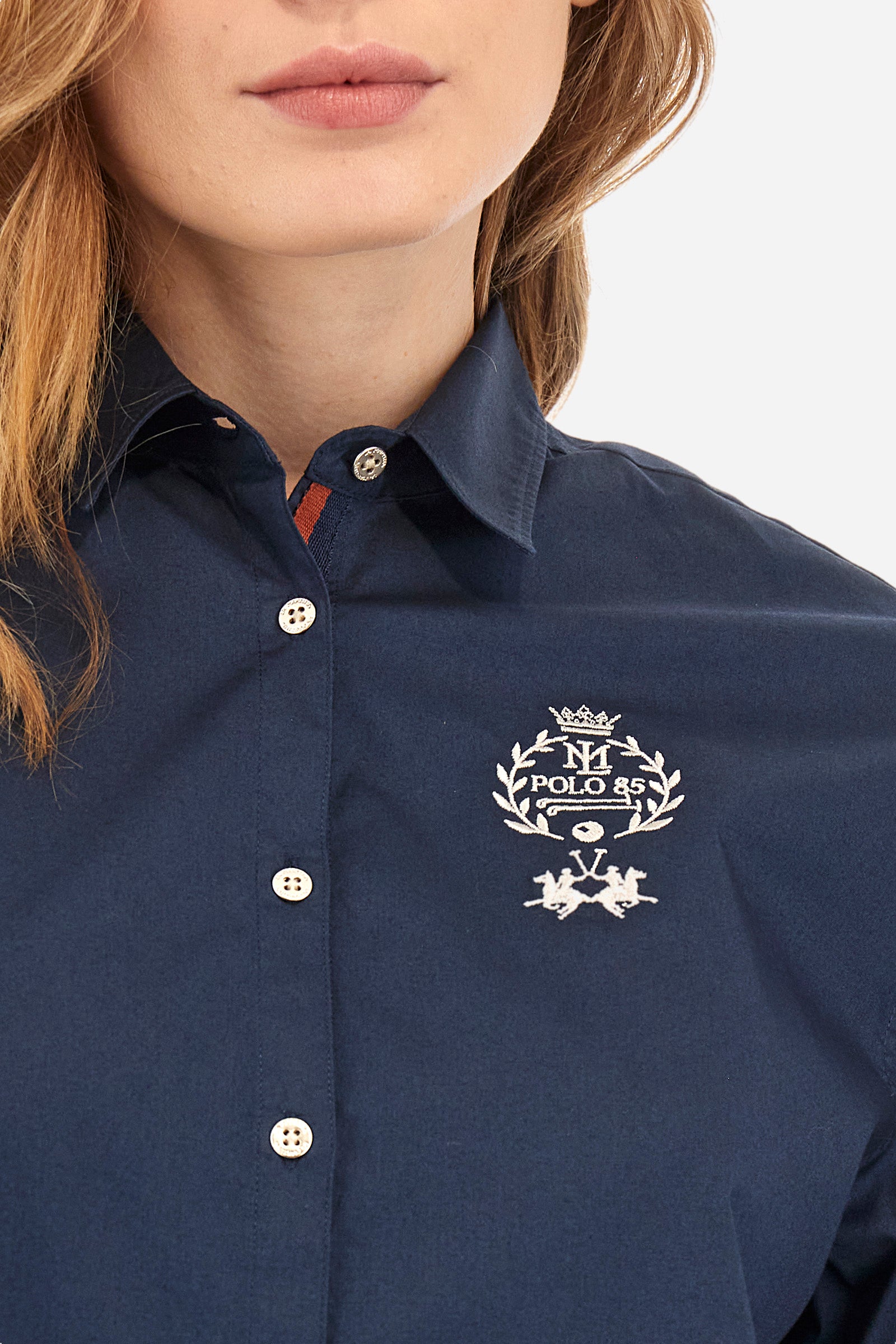 Women's long-sleeved patterned shirt in a single colour from the Polo Academy line. Made of stretch cotton. The internal part of the fastening features a touch of colour that contrasts with the main one. The logo and symbol of the Polo Academy line are sewn on the back. With buttoned cuffs. The logo is present on the back on a metal plate sewn onto a coloured strip. The fit is regular. The model wears a size 2. - Navy