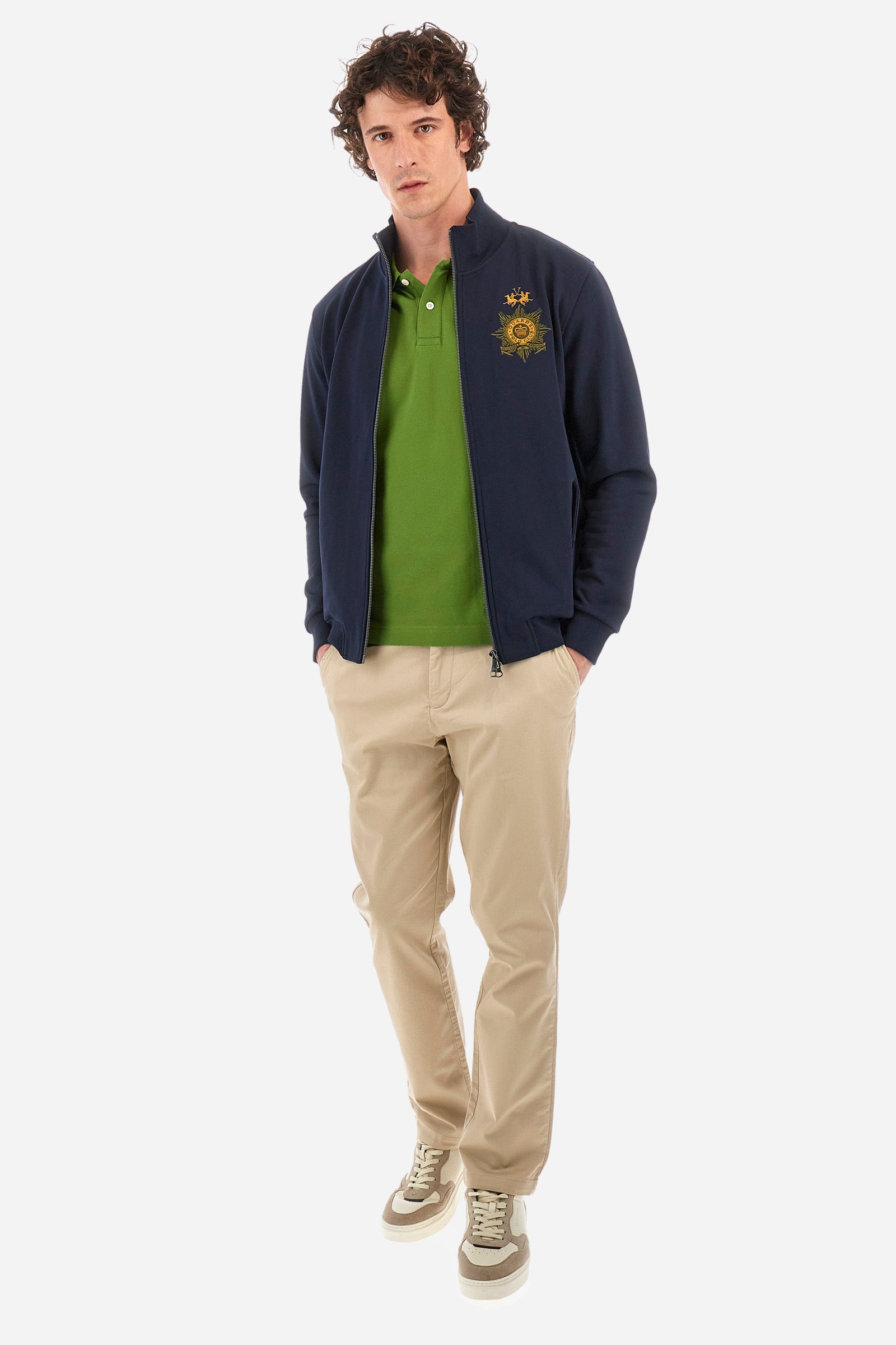 Men’s solid color long sleeve sweatshirt with full zip closure. Made of 100% cotton. High neck with drawstring, ribbed hem and cuffs. Double front pocket with button closure. Writing and large symbol on the chest identify the capsule collection. The fit is regular. The model wears a size L. - Navy