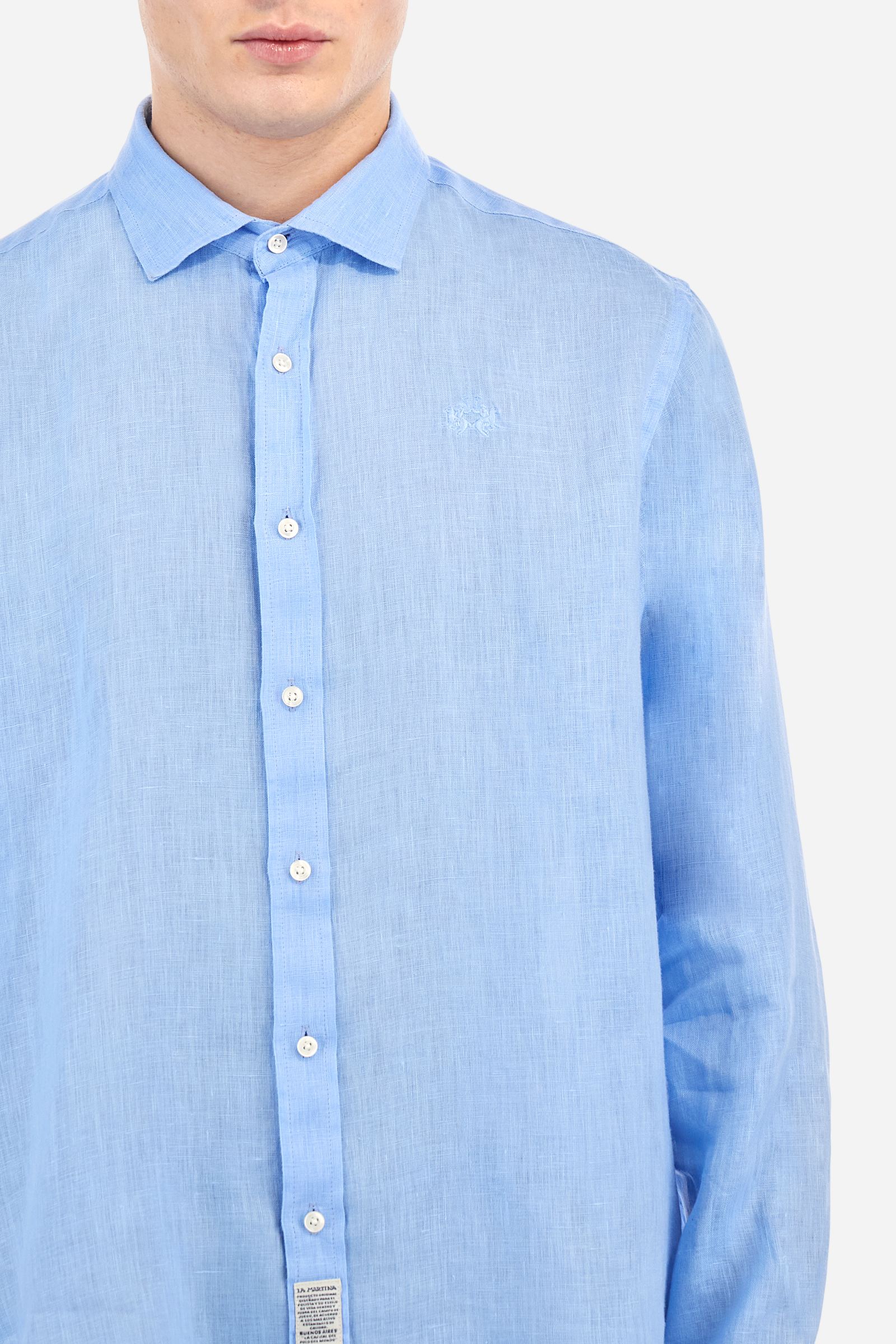 Men's plain long-sleeved shirt made from linen canvas. Button-down collar. Two fabric patches, depicting the brand's certification and the Argentine flag, are sewn on the hem of the garment. A tone-on-tone logo is embroidered on the left side of the chest. Regular fit. The model is wearing a size L. - Vista Blue