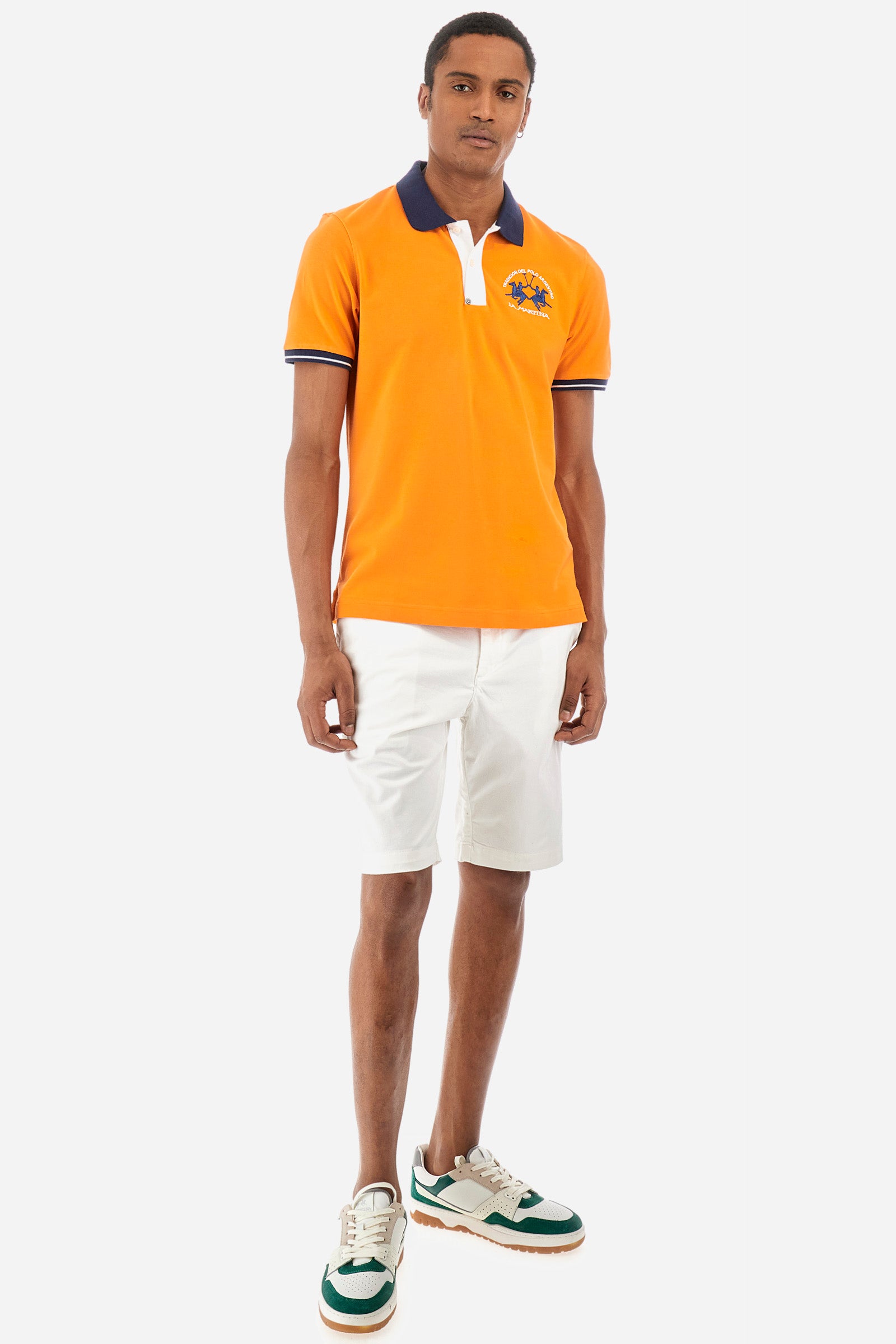 Men's single-colour short-sleeved polo in elasticated cotton. Fastens with two contrasting buttons. Ribbed collar and armholes in different shades. The "La Martina" lettering can be found under the collar. A large logo is embroidered on the chest. The fit is slim. The model wears a size L. - Celosia Orange