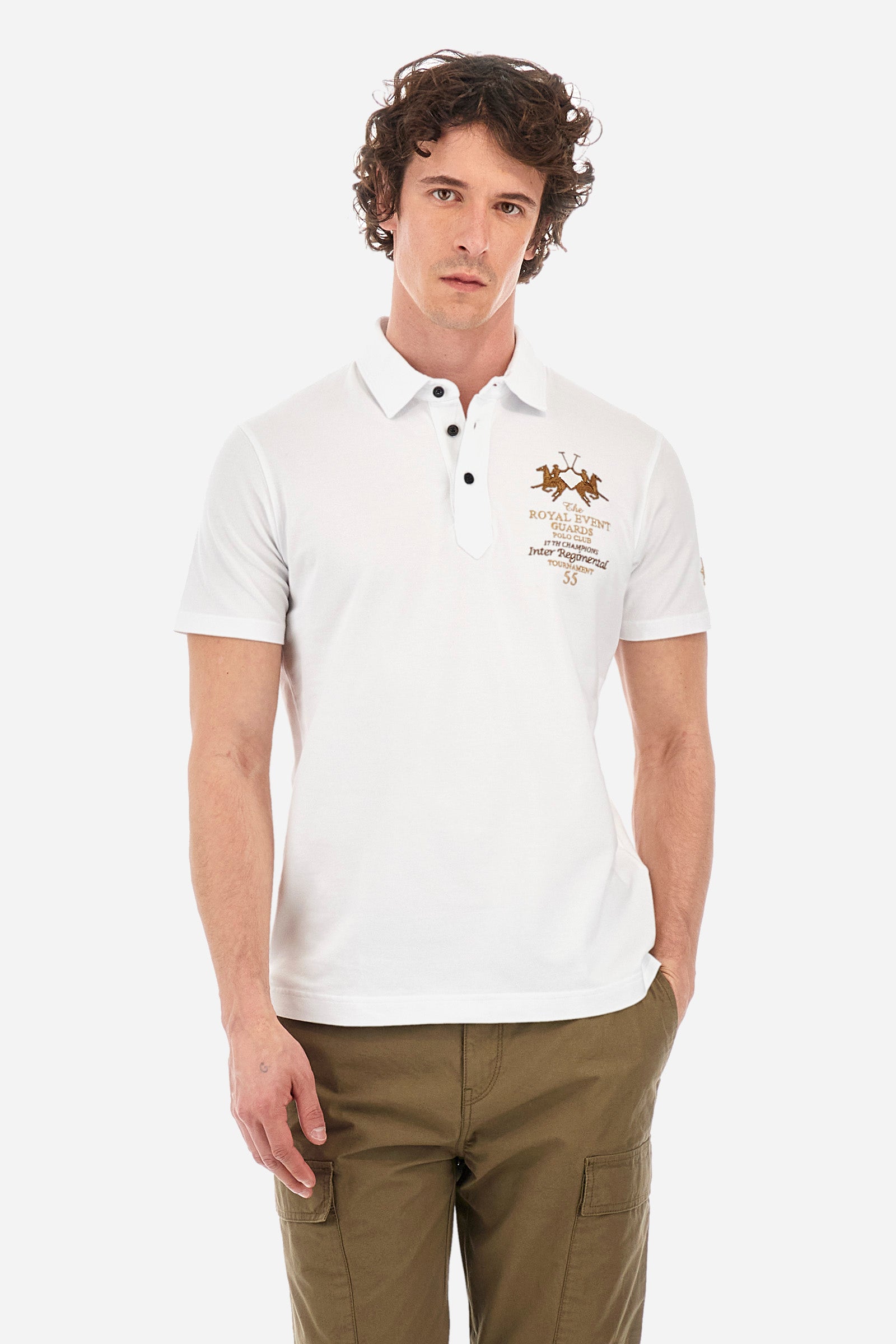Men's short-sleeved single-colour polo shirt in elasticated cotton. Two-button fastening. Pointed collar. On the front we find copper-coloured lettering and a large logo. On one of the sleeves there is a symbol representing the Guards line. The fit is regular. The model wears a size L. - Optic White
