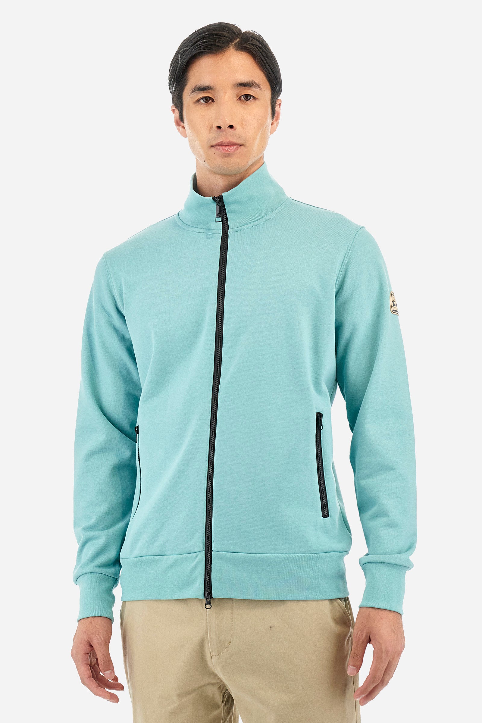 Men's long-sleeved solid-coloured sweatshirt with contrasting zip. Made of cotton. Equipped with a full zip and double front pocket, also with zip fastening. One sleeve features an applied logo patch. The fit is regular. The model wears a size L. - Aquifer