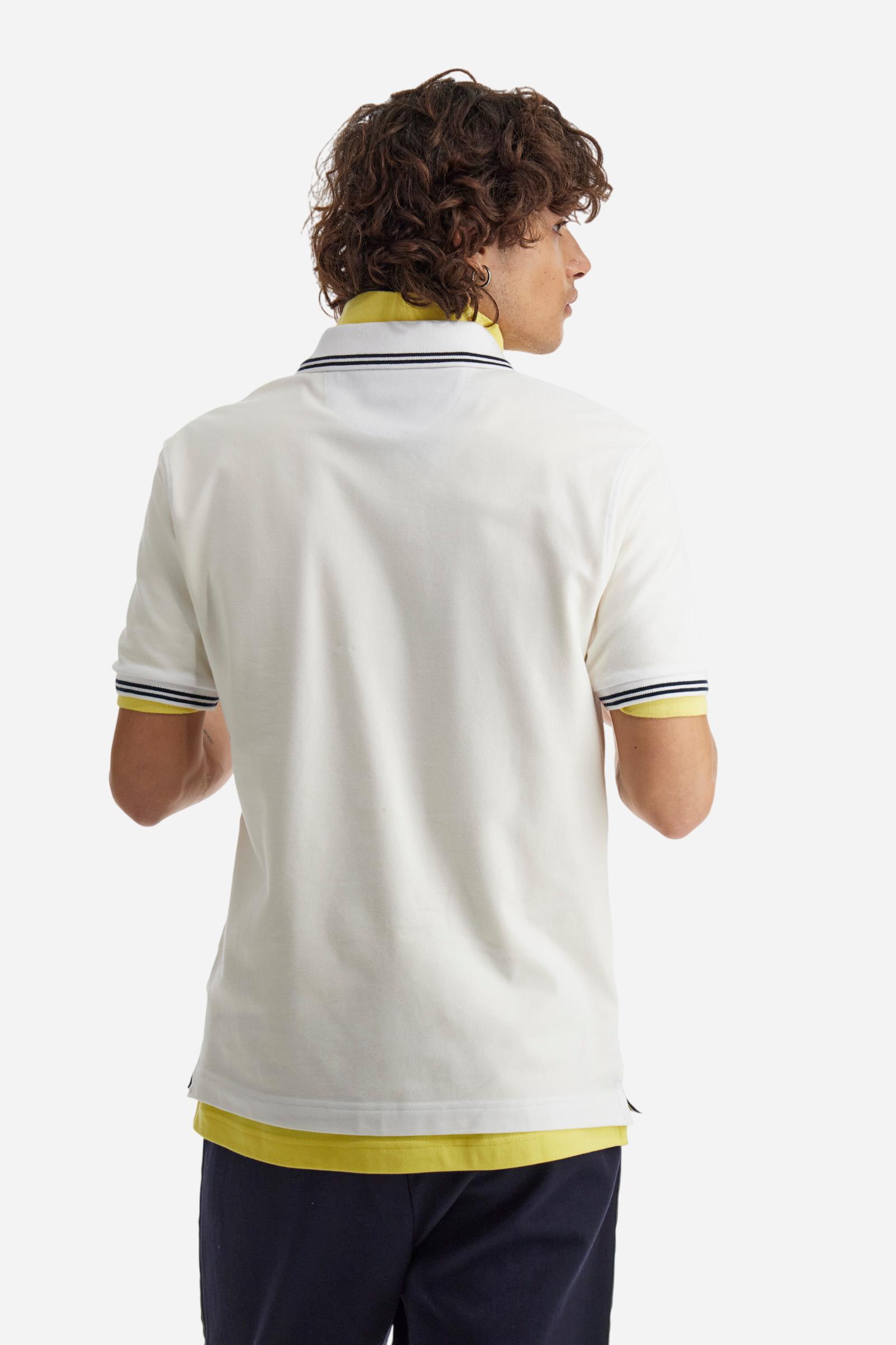 Men's plain short-sleeved polo shirt made from stretch piqué. Two-button fastening. The collar and cuffs are made from two-tone striped ribbed fabric. The inside of the collar and placket feature contrasting fabrics and colours. There is a two-tone striped band around the inside of the collar. The right sleeve and chest are embroidered in tone-on-tone thread. A logo is embroidered on the left sleeve, also using tone-on-tone thread. Regular fit. The model is wearing a size L. - Optic White